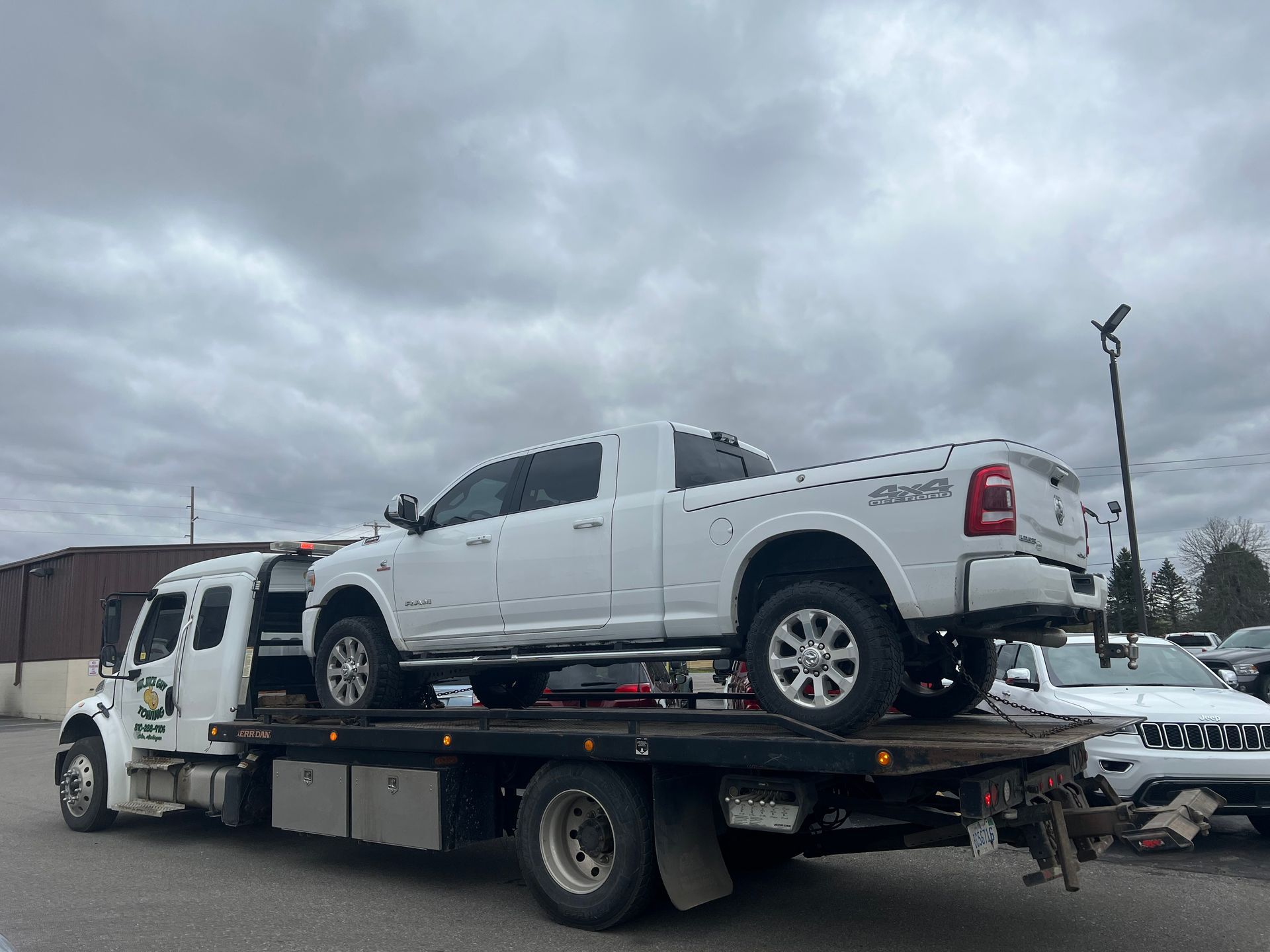 A white truck is being towed by a tow truck.