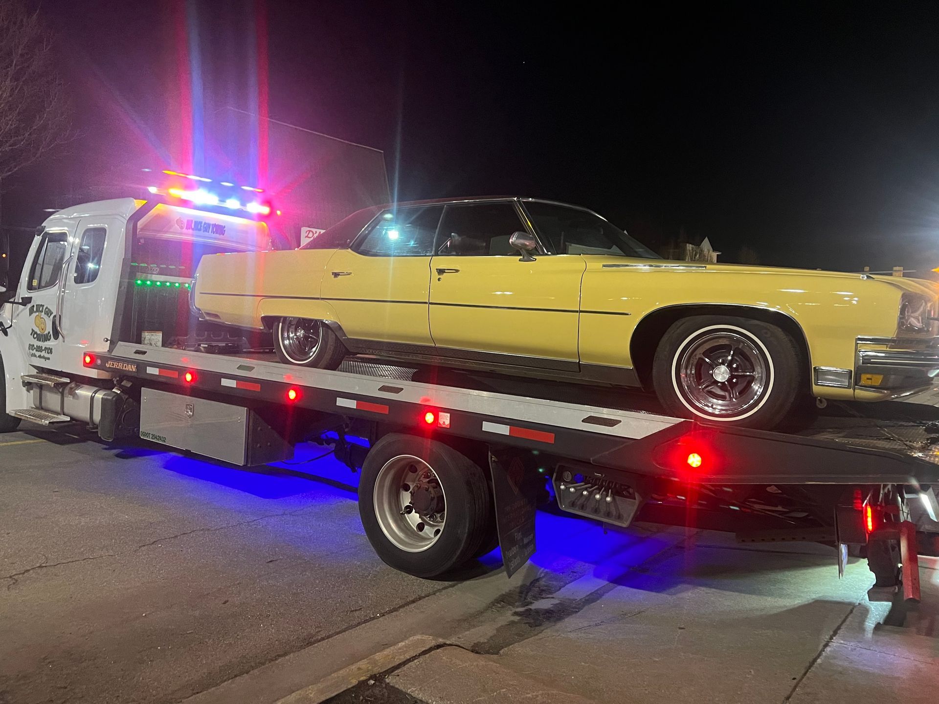 A yellow car is being towed by a tow truck.