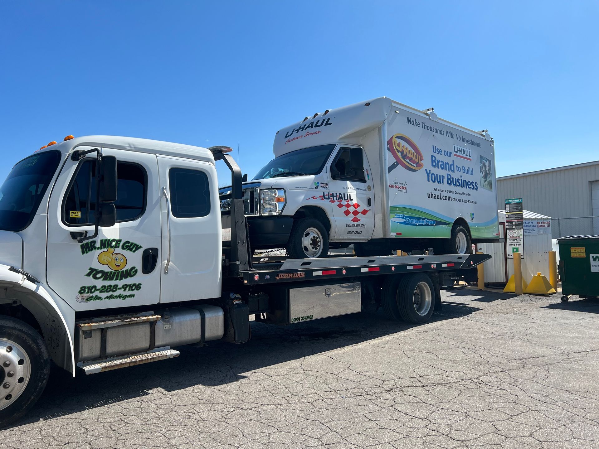 A tow truck is carrying a van on the back of it.