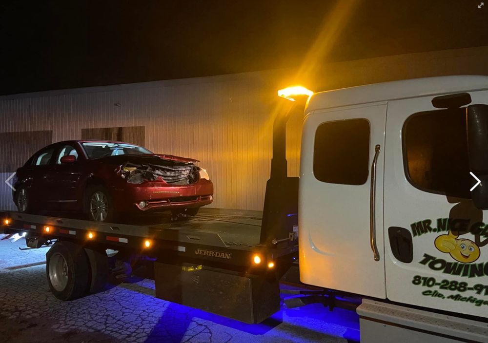 A red car is sitting on top of a tow truck.