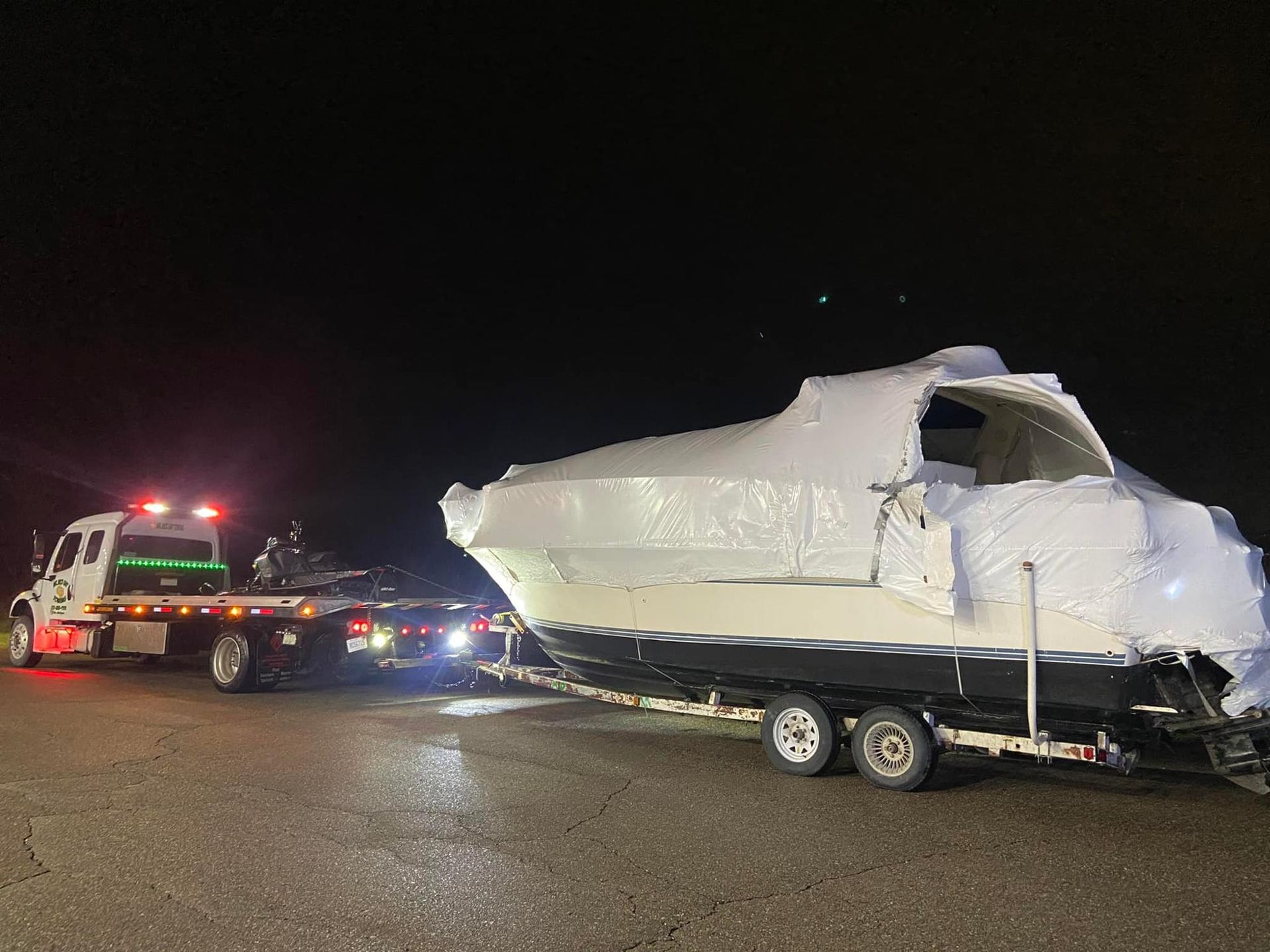 A boat is being towed by a tow truck at night.
