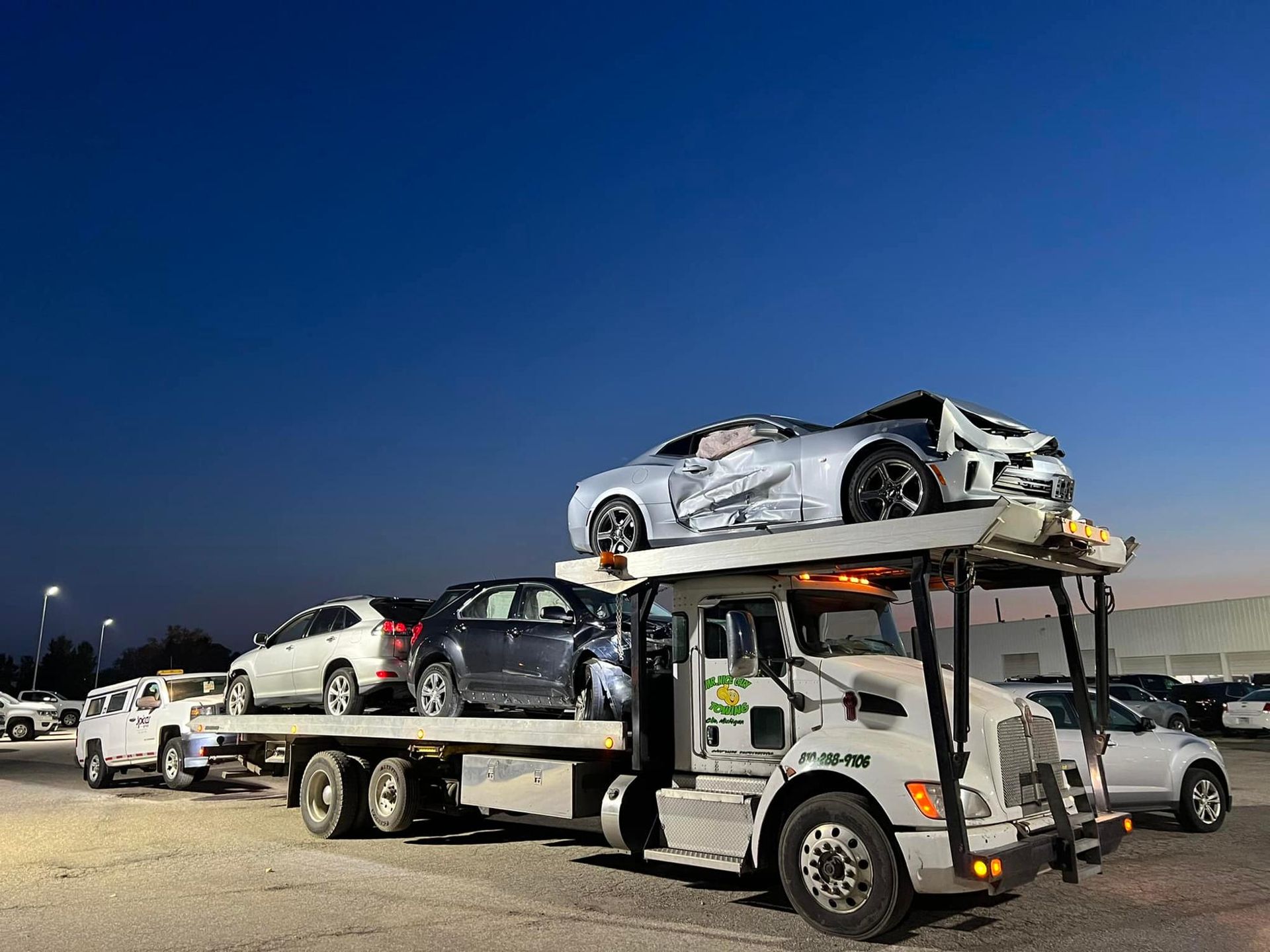 A tow truck is carrying a stack of cars on top of it.