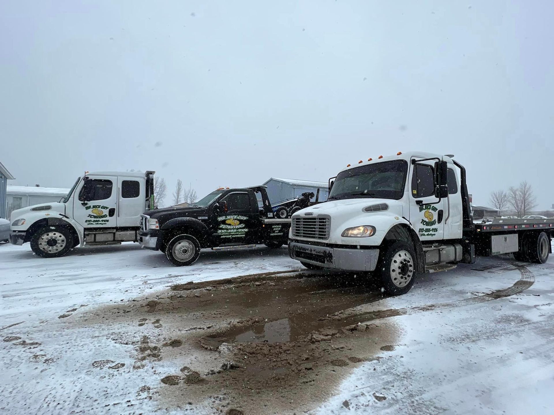Two tow trucks are parked next to each other in the snow.