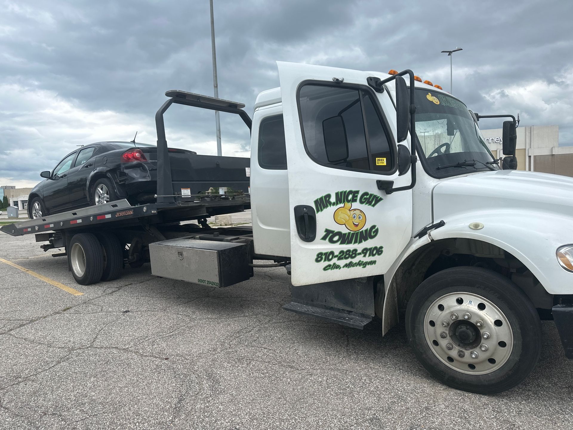 A tow truck is towing a car in a parking lot.