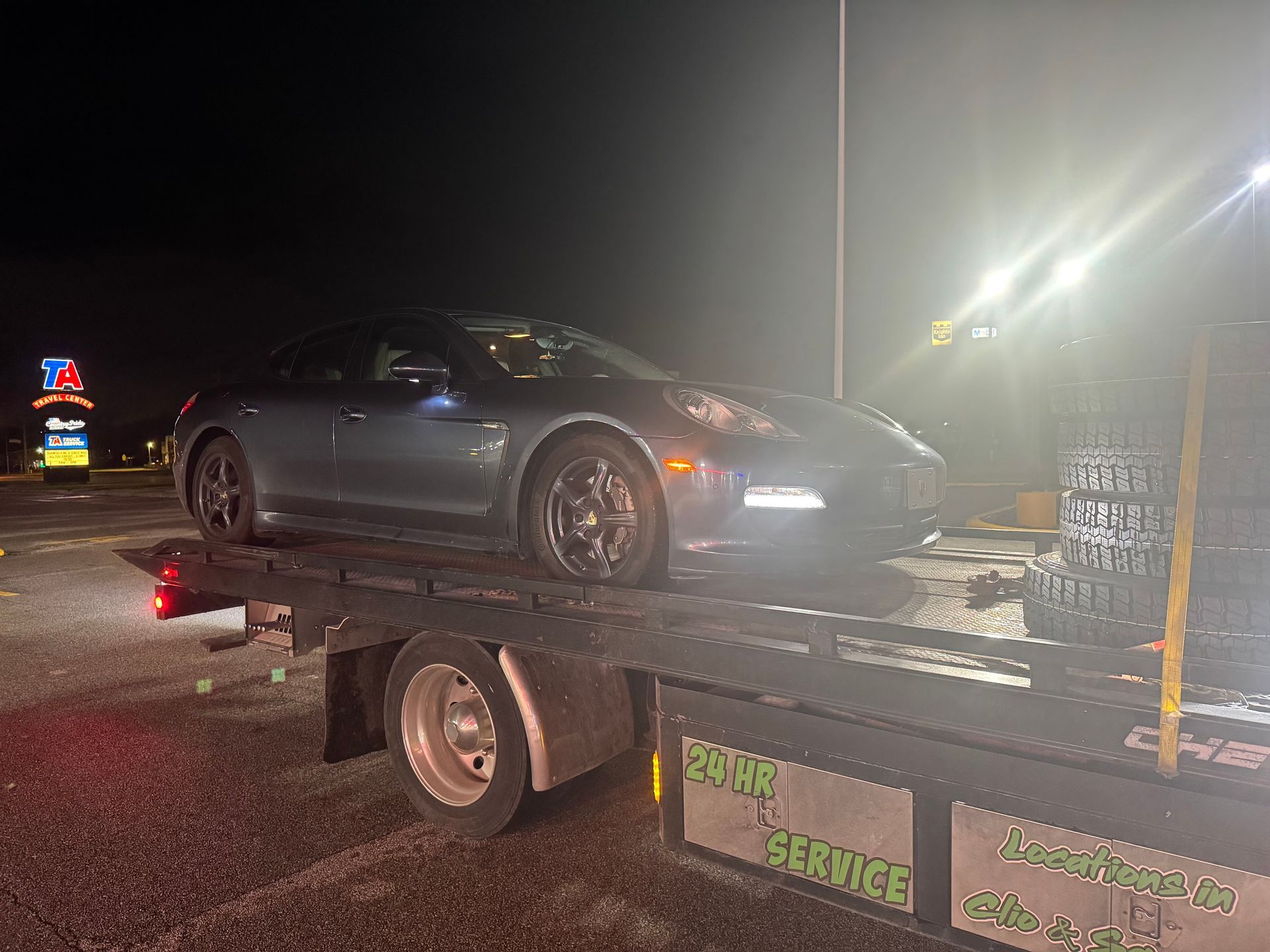 A car is being towed by a tow truck at night.