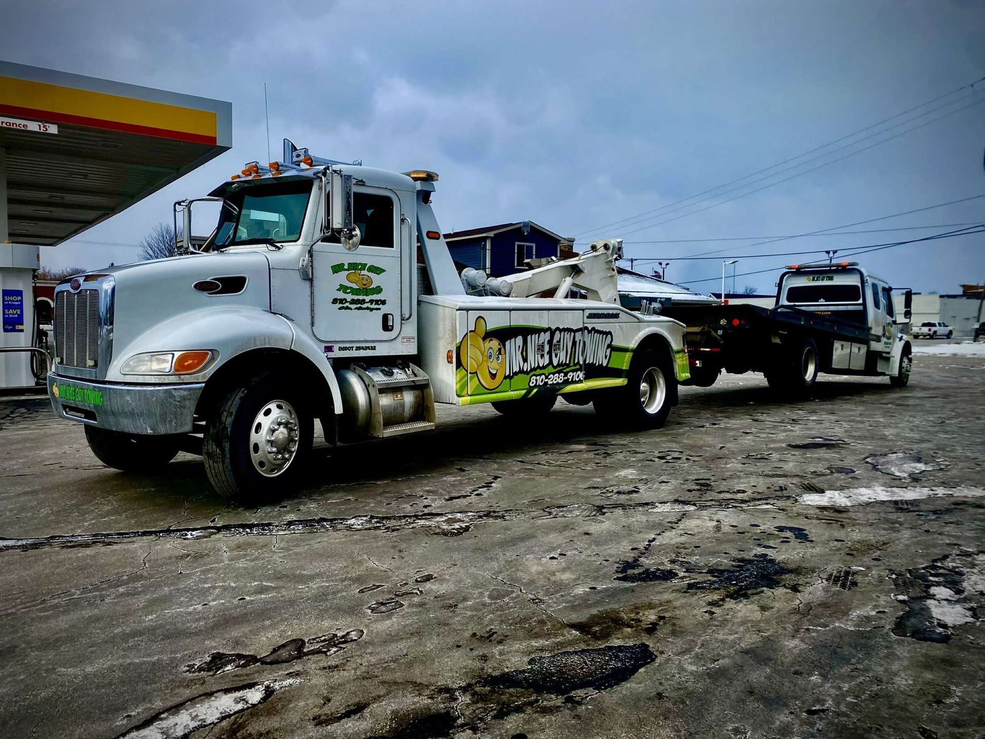A tow truck is parked in front of a gas station.