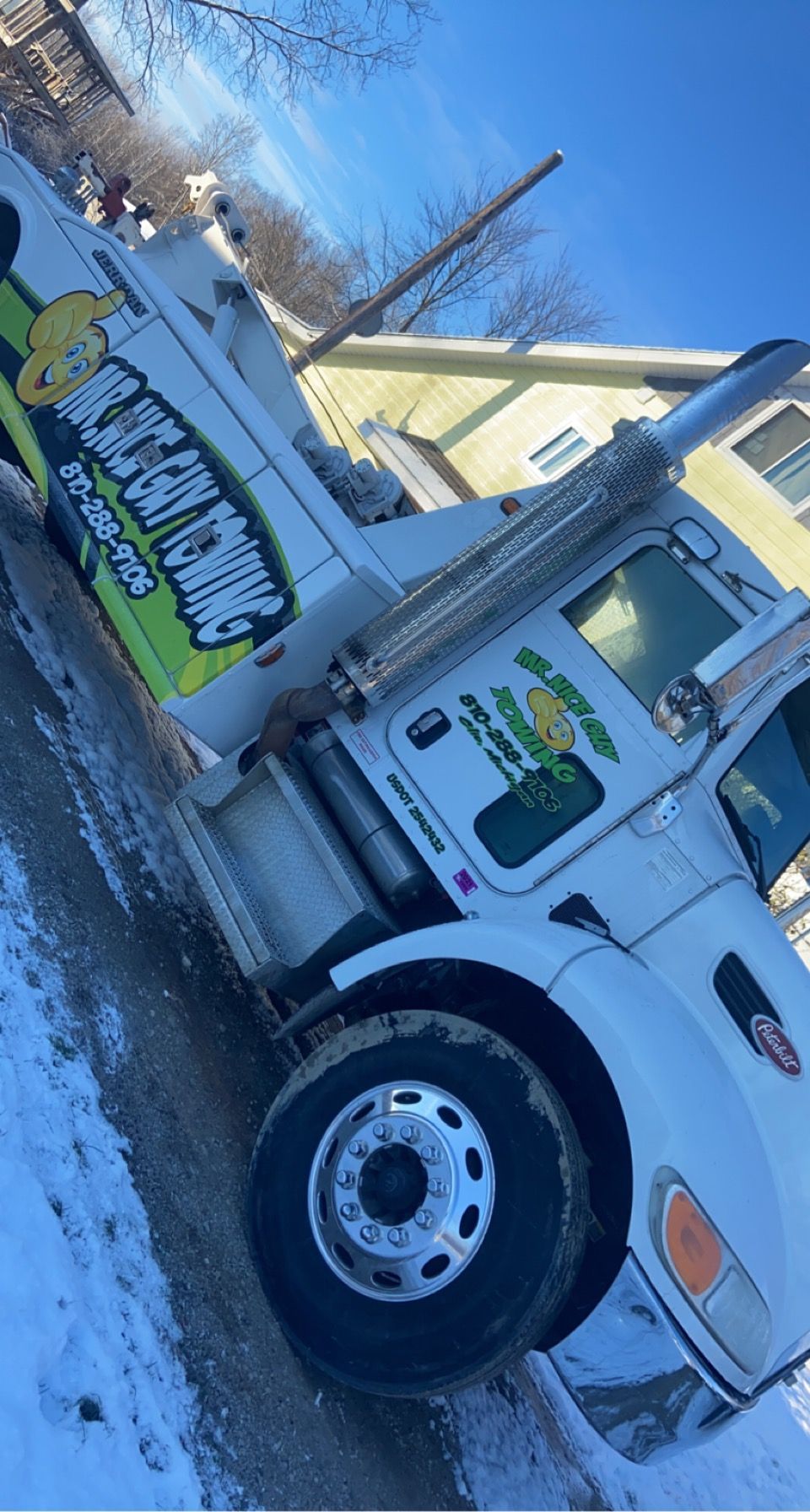 A white tow truck is parked on the side of the road in the snow.