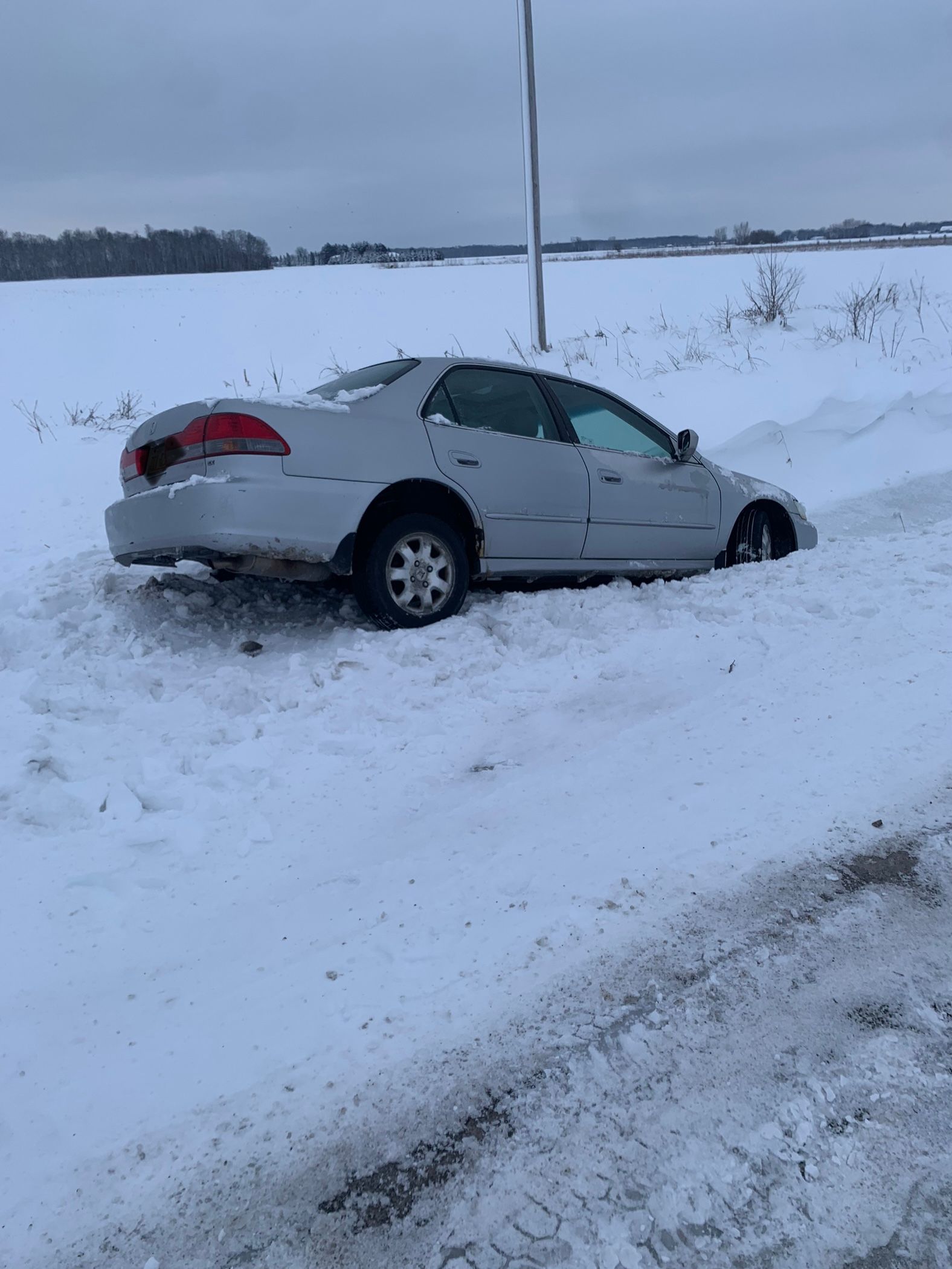 A car is stuck in the snow on the side of the road.