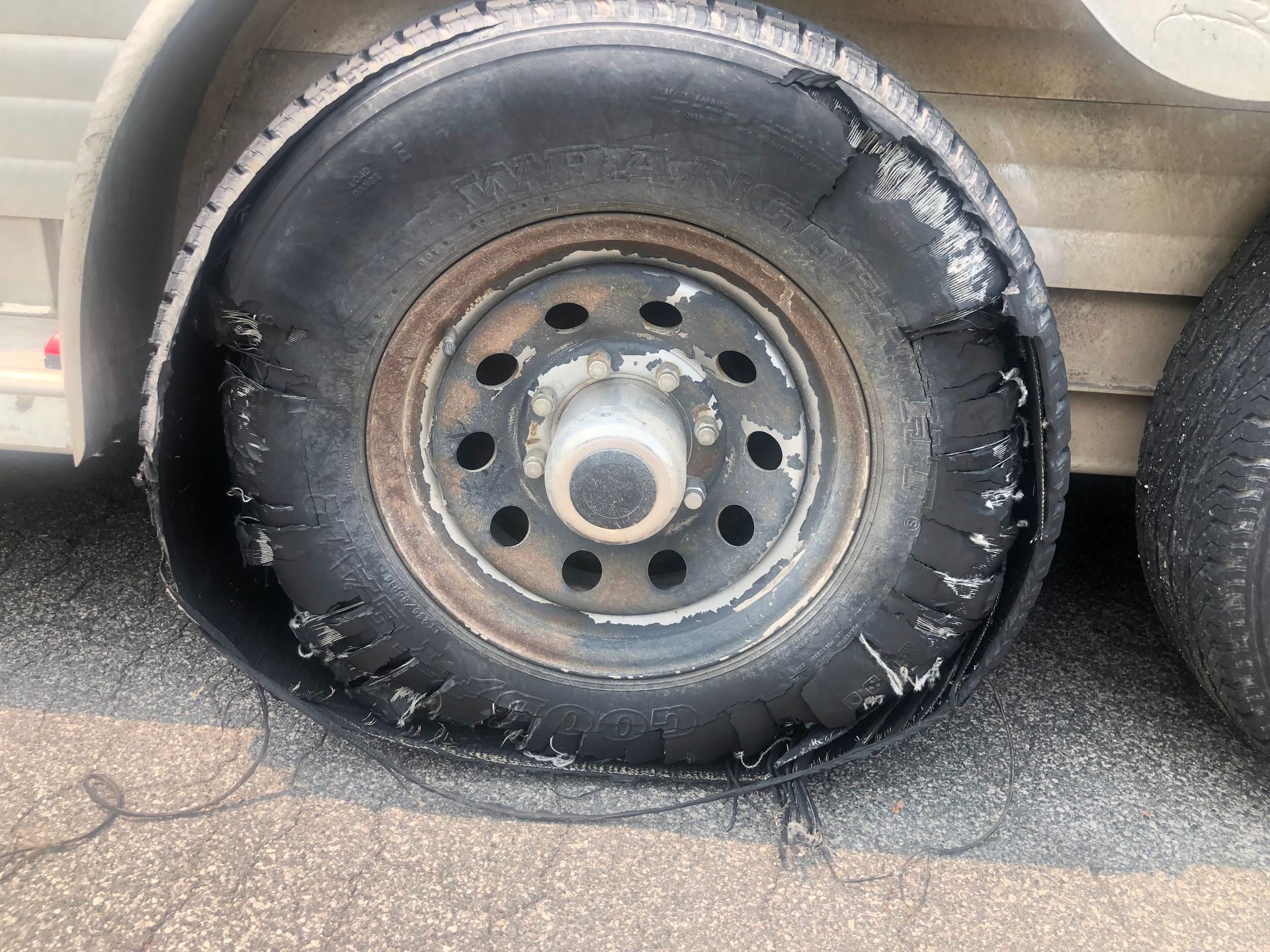 A truck with a flat tire is parked on the side of the road.