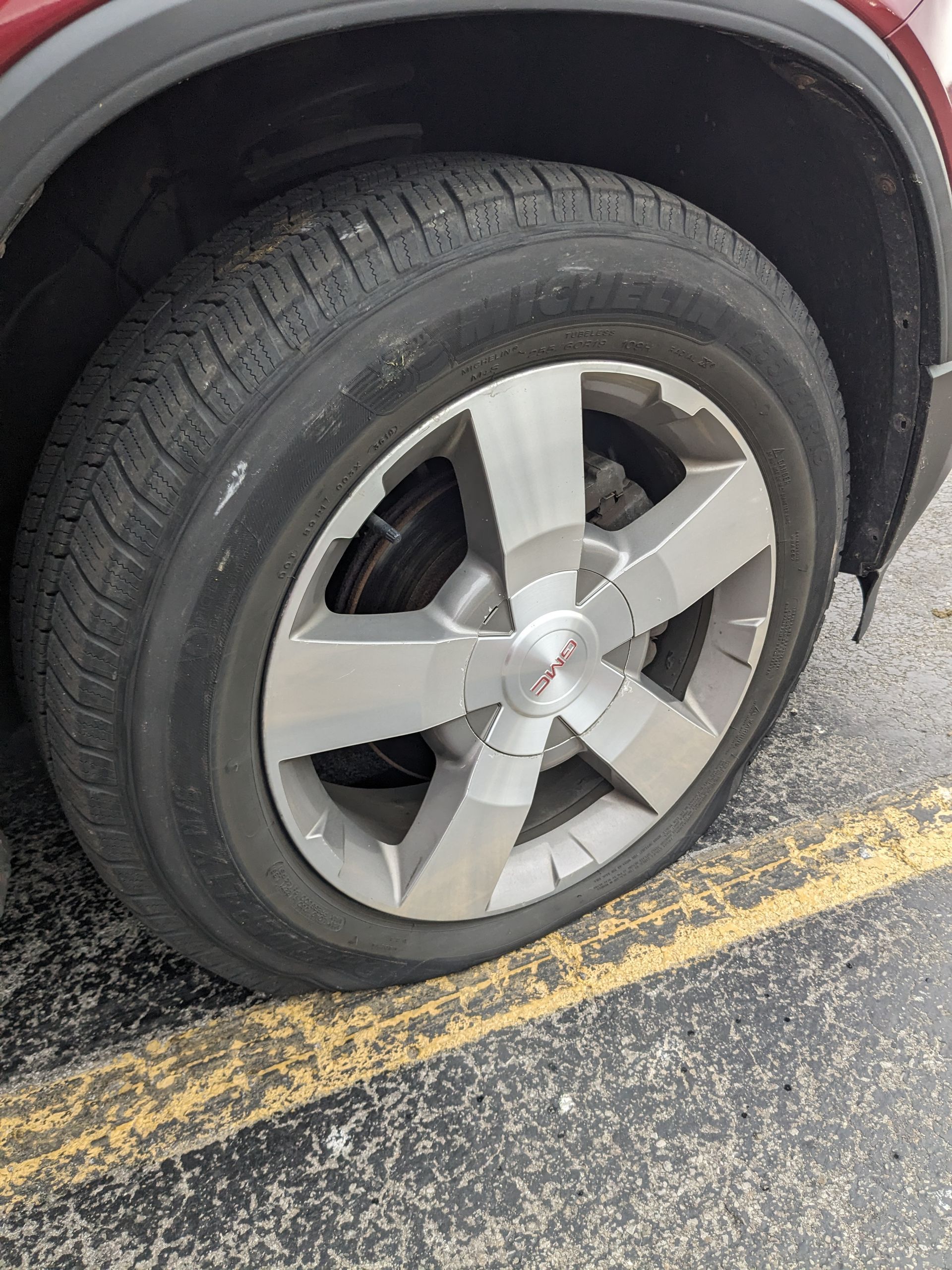 A car with a flat tire is parked in a parking lot