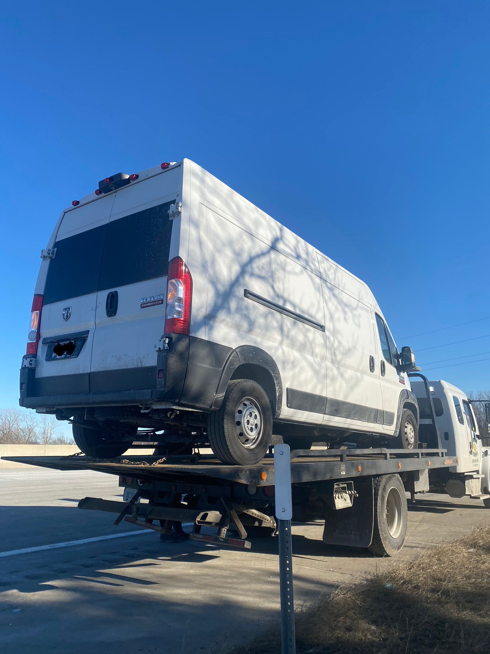 A white van is being towed by a tow truck.
