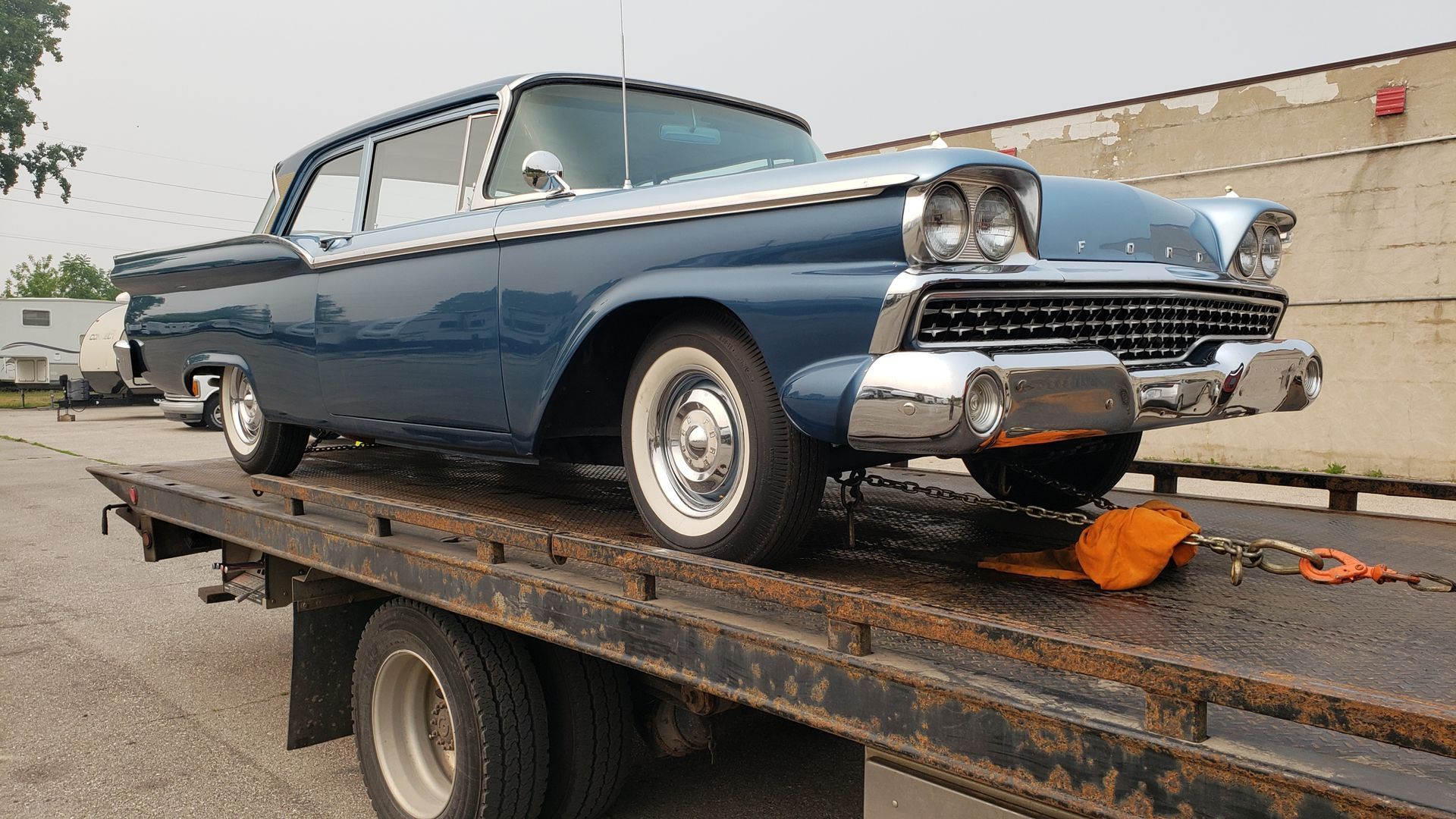 A blue car is sitting on top of a tow truck.