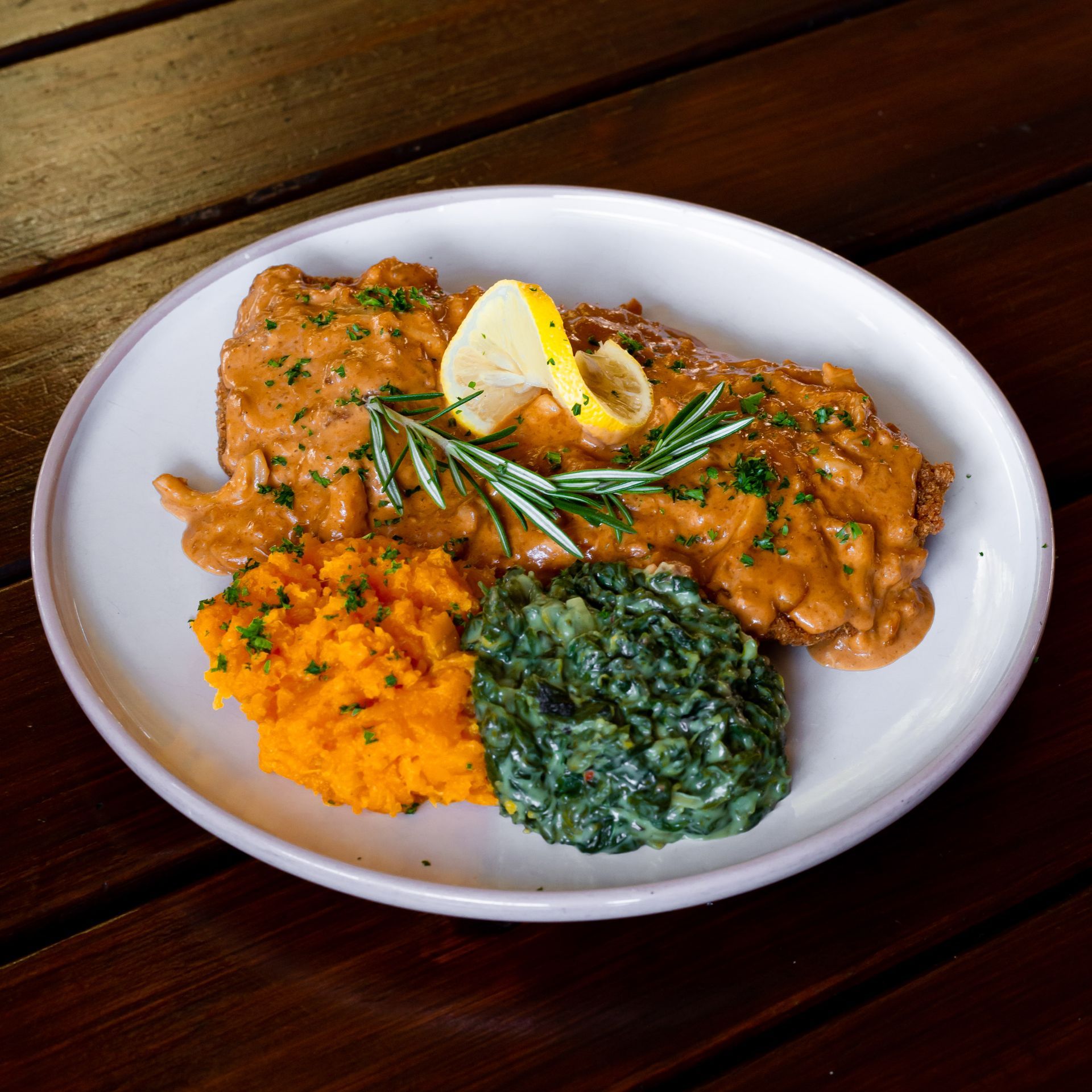 A plate of food with mashed potatoes and spinach on a wooden table