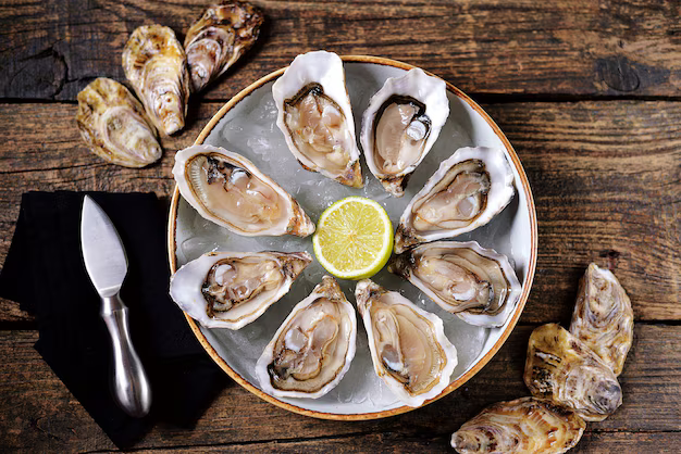 A plate of oysters with ice and a lemon on a wooden table.