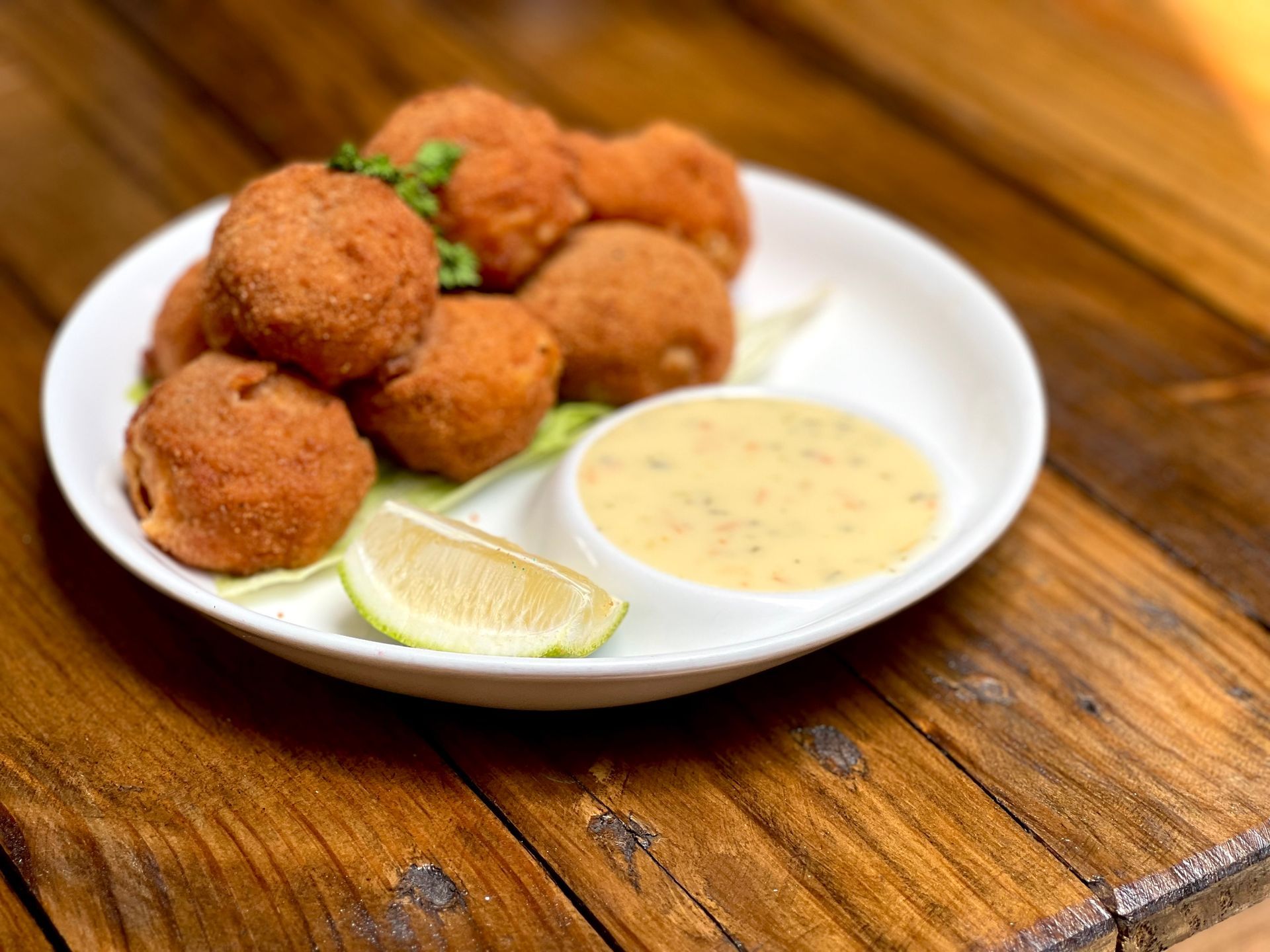 A white plate topped with fried food and a dipping sauce on a wooden table.