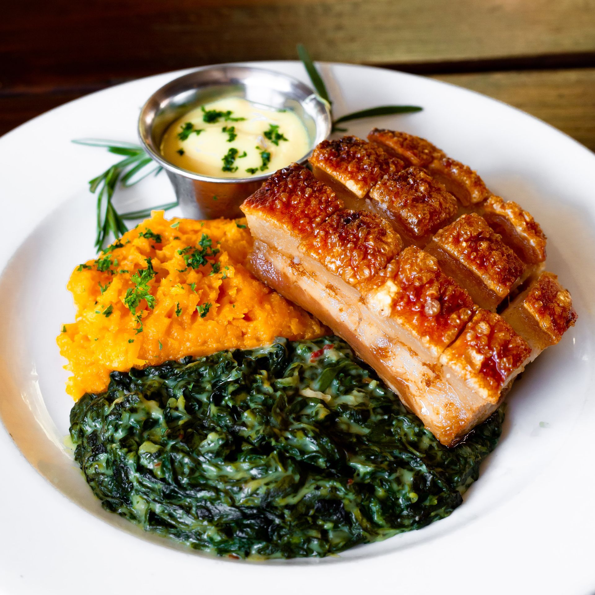 A white plate topped with a piece of meat mashed potatoes and spinach