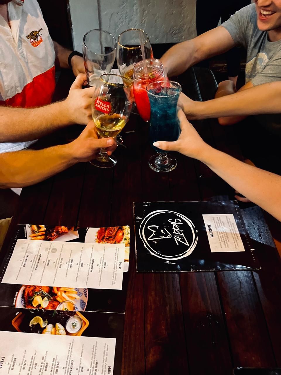 A group of people are sitting at a table toasting with drinks.