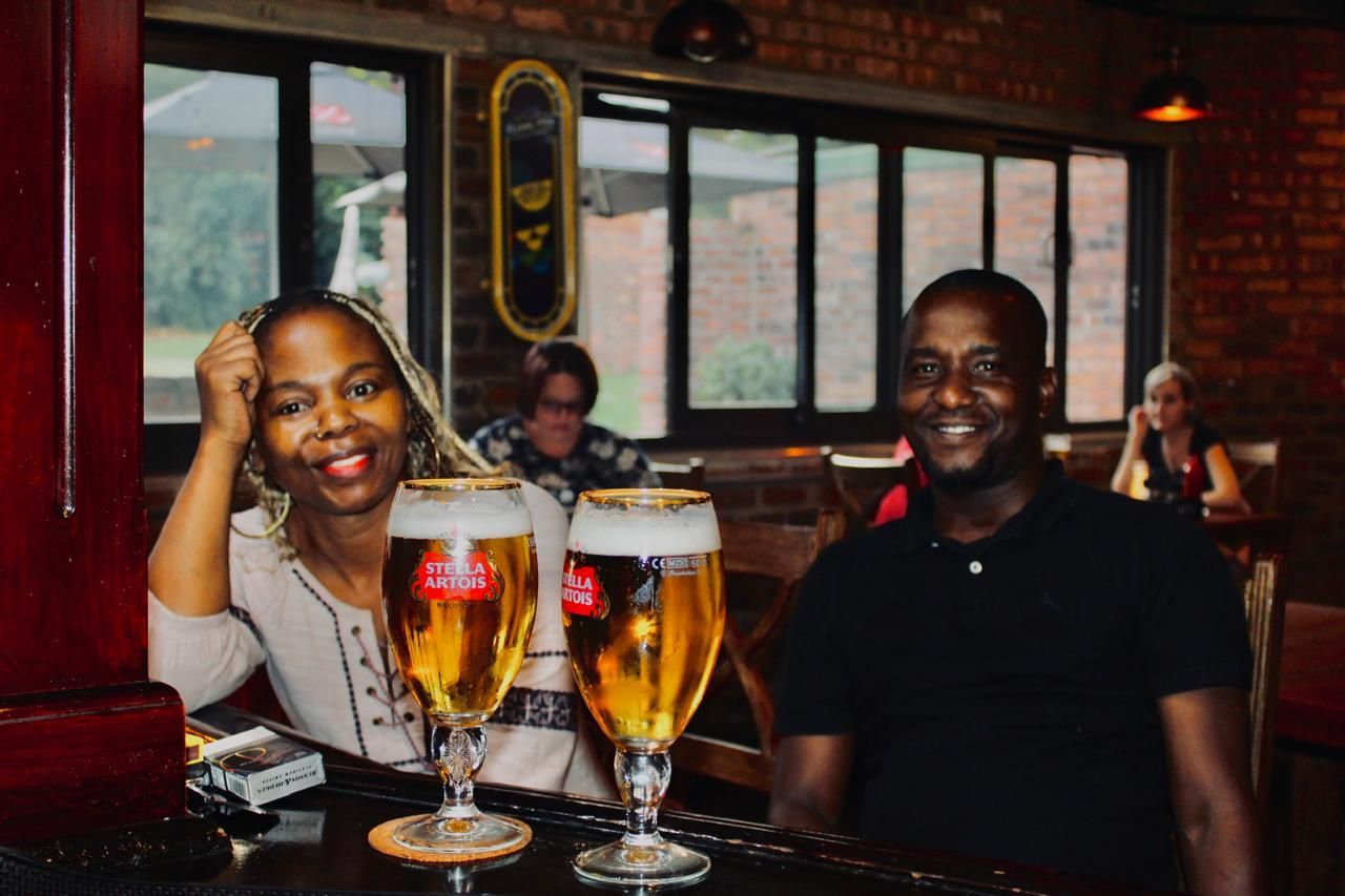A man and a woman are sitting at a bar with two glasses of beer.