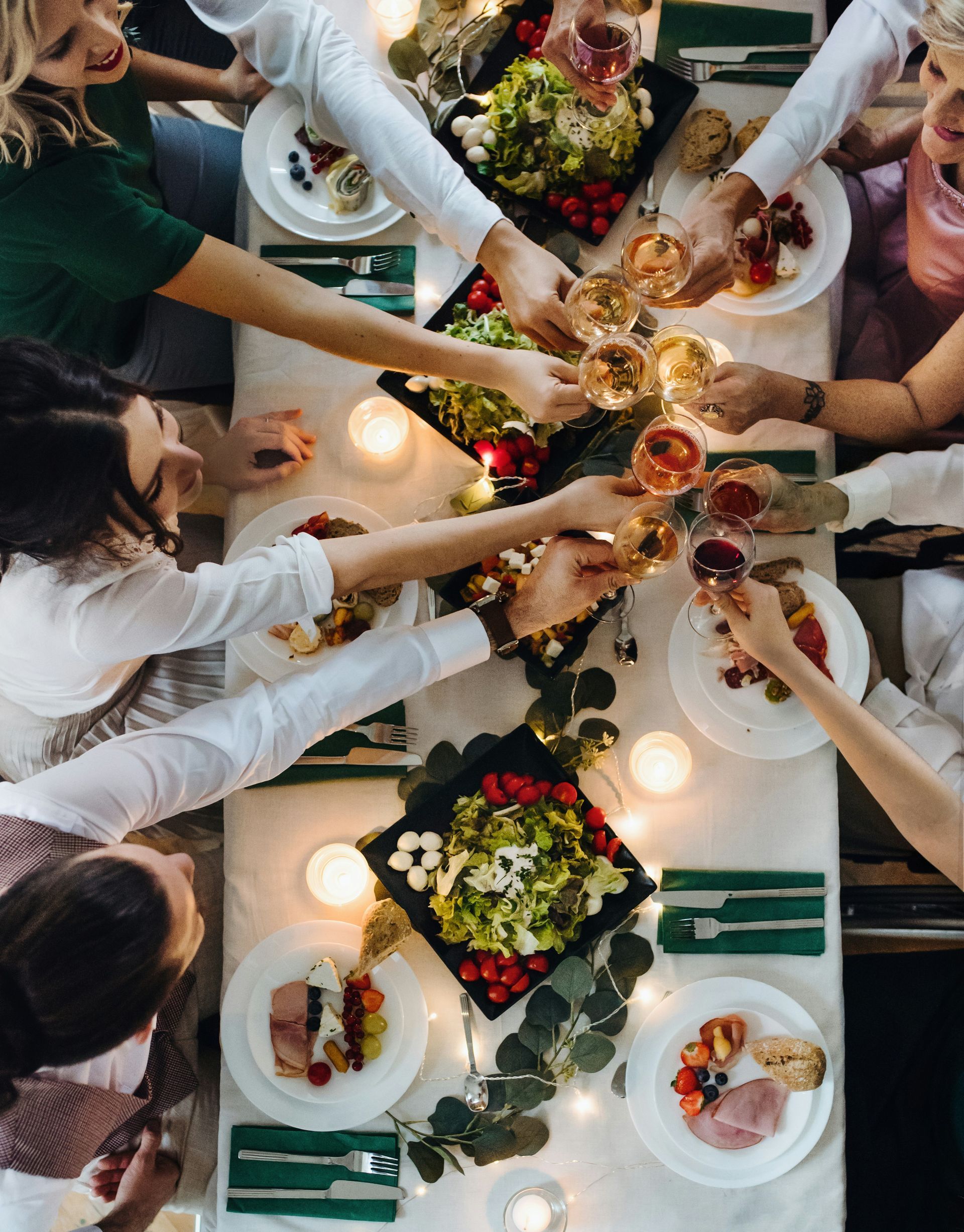 A group of people are sitting around a table eating food and drinking wine.