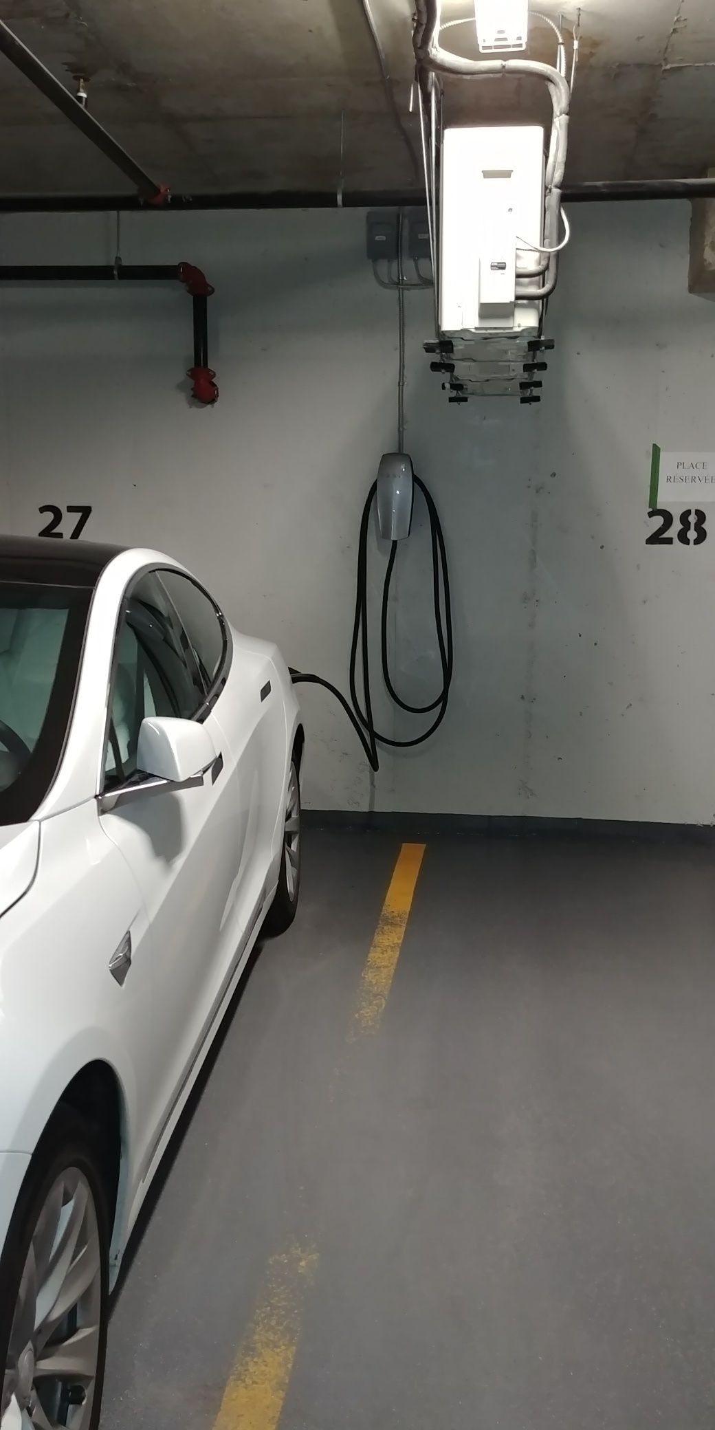 Une voiture blanche est chargée dans un parking.