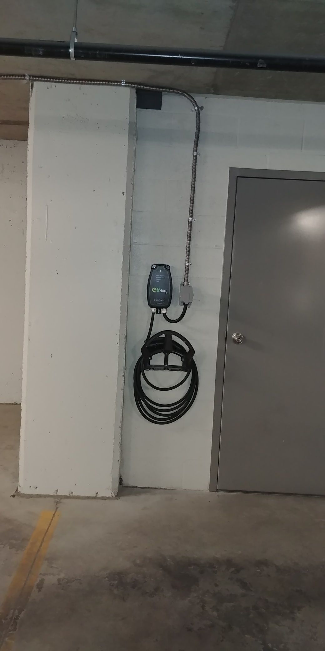 Un chargeur de voiture est fixé à un mur dans un parking.