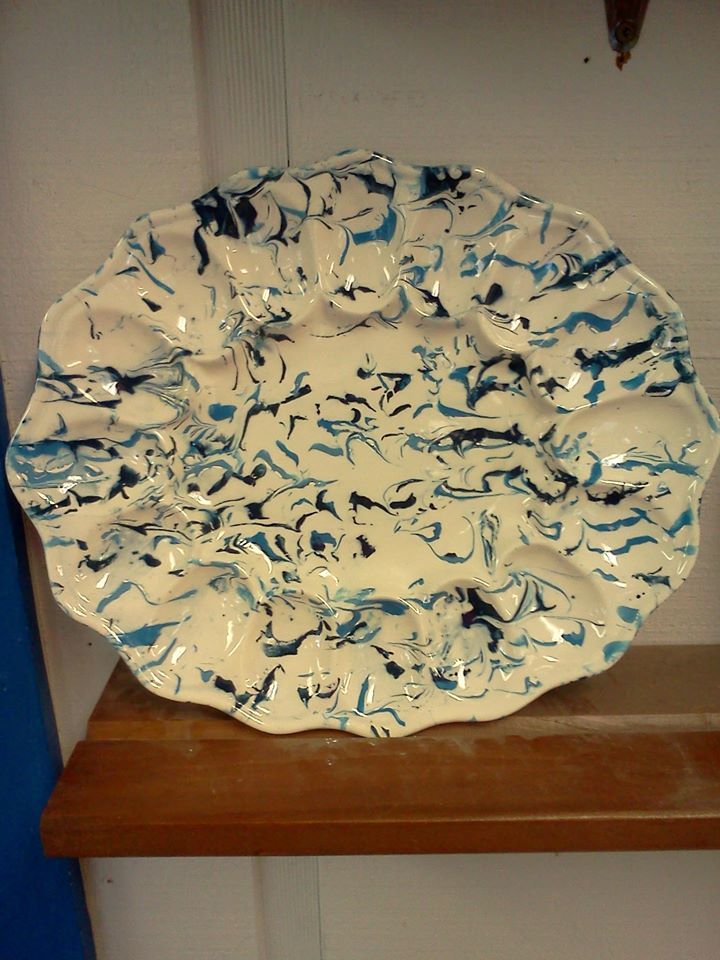 A blue and white plate is sitting on a wooden shelf