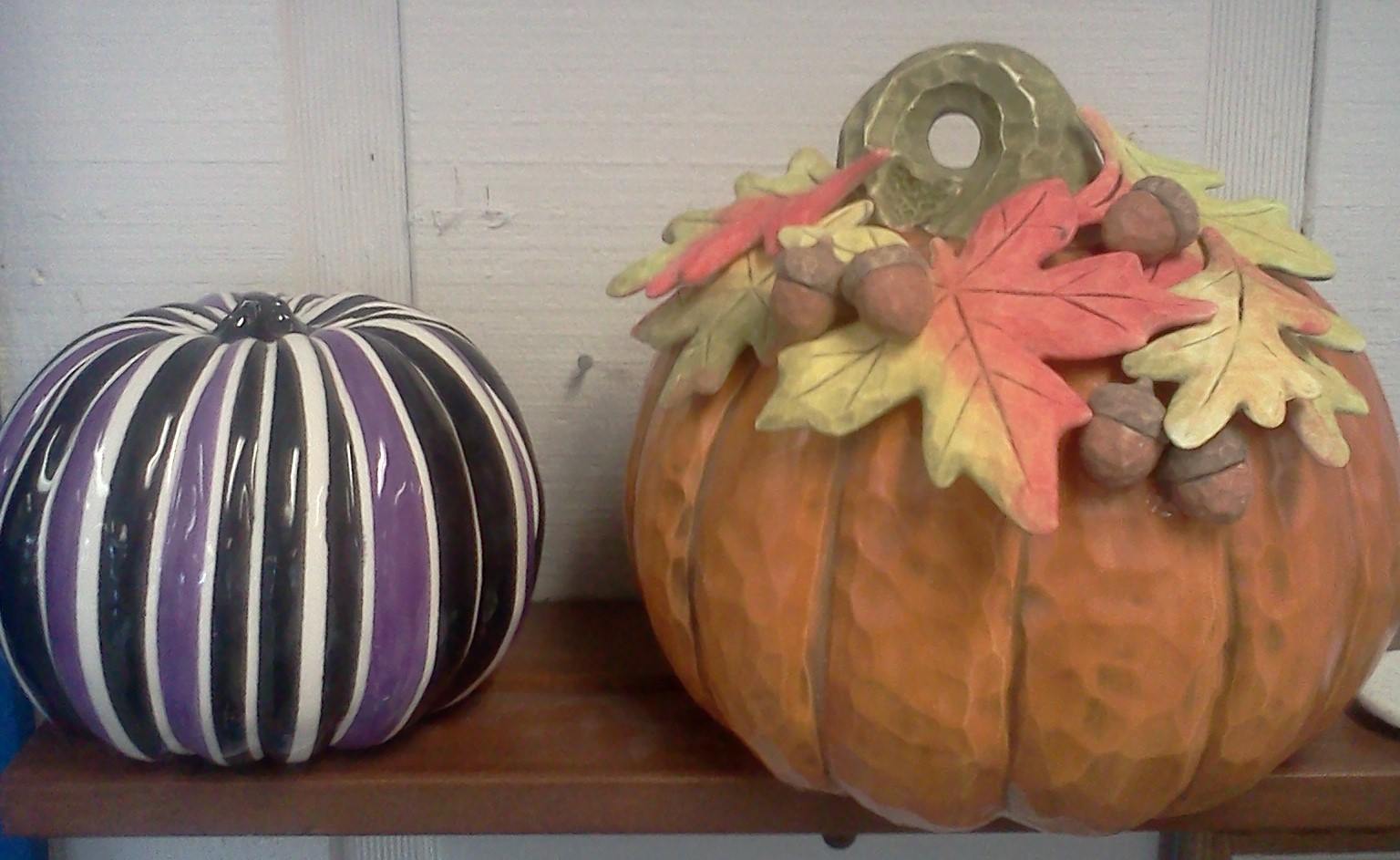 Two pumpkins with leaves and acorns on them are on a shelf