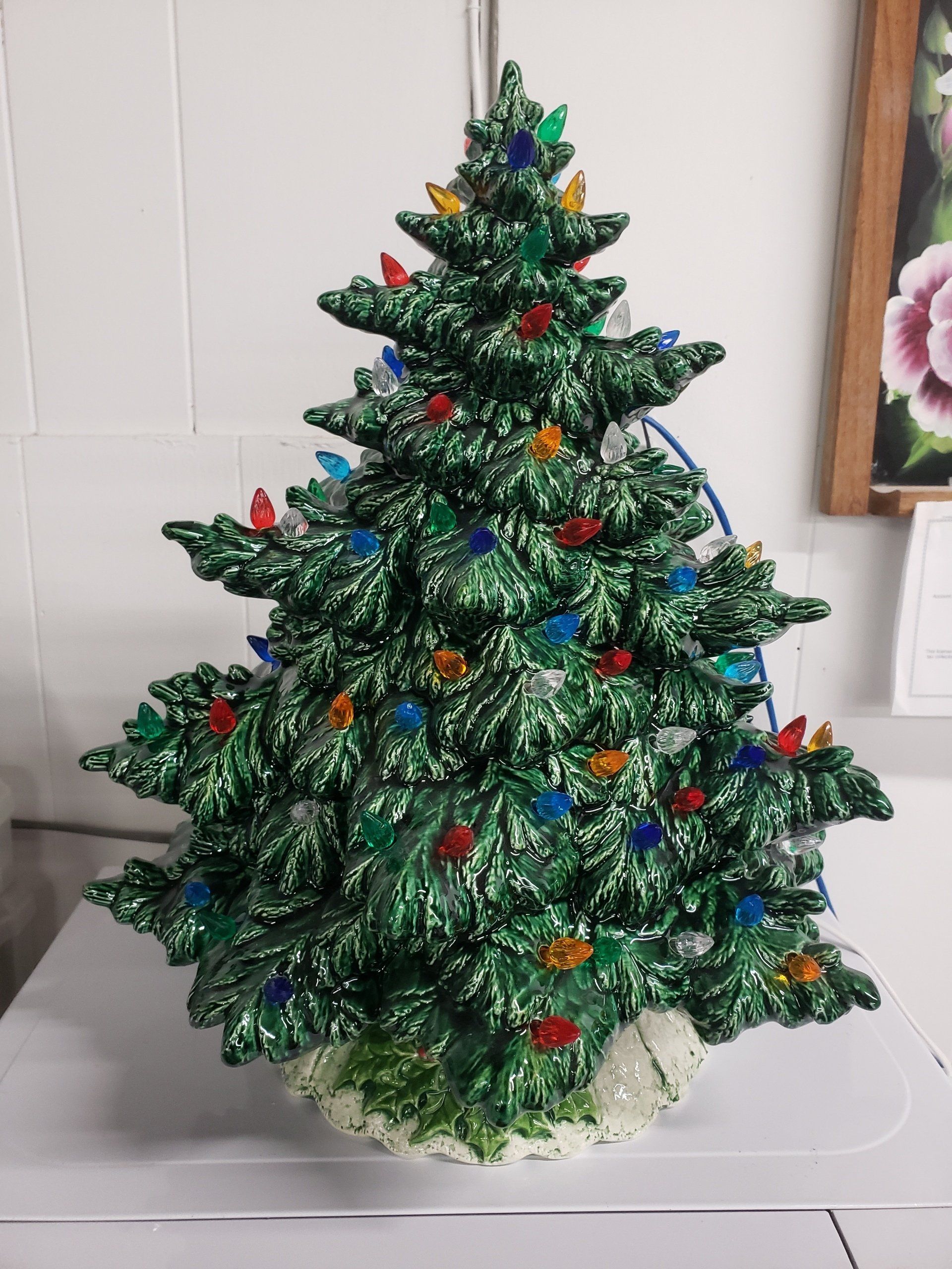 A green ceramic christmas tree with lights on it