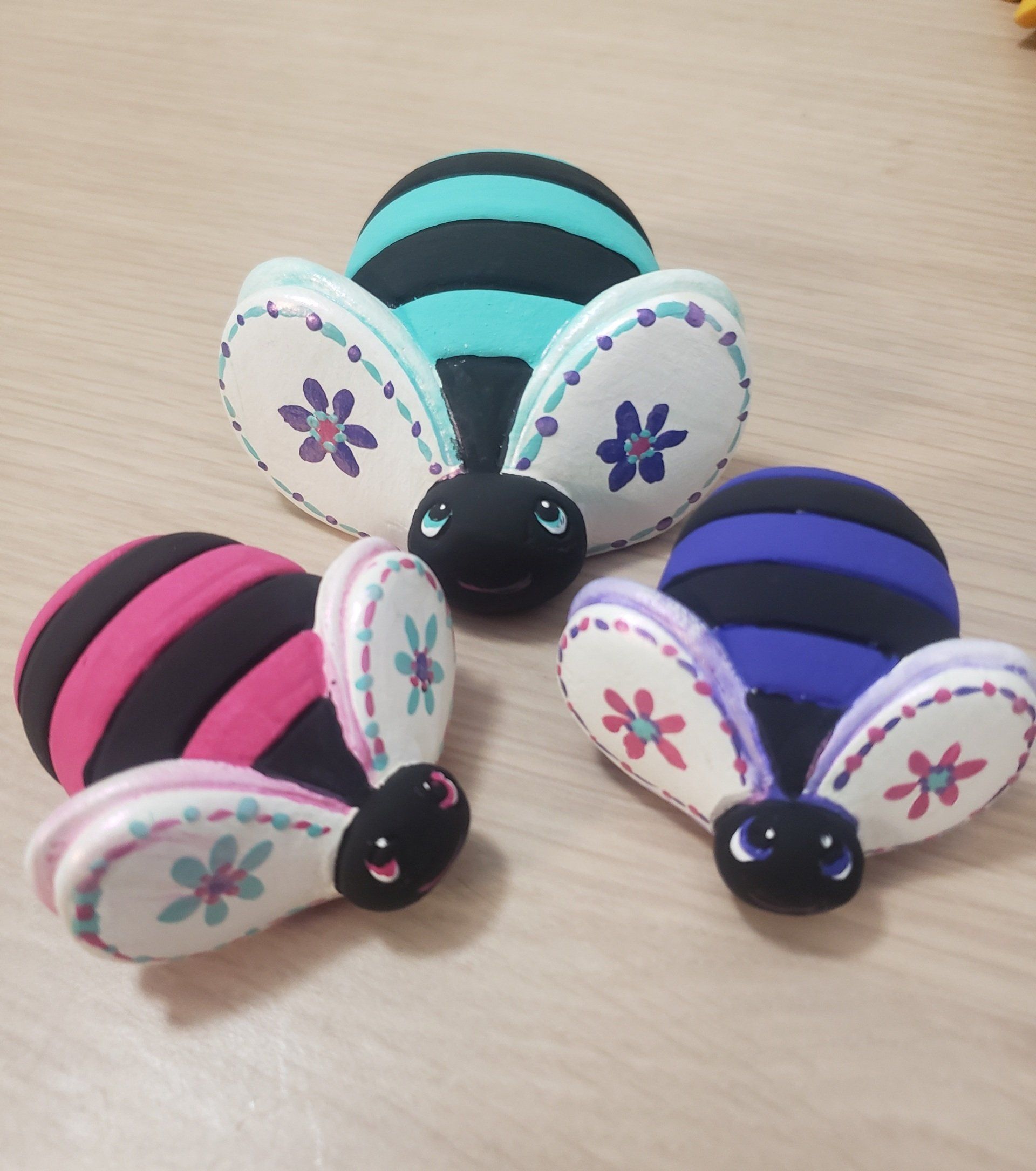 Three stuffed bees with flowers on their wings are sitting on a table
