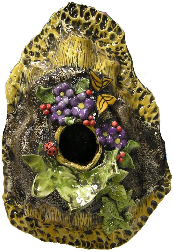A ceramic birdhouse with purple grapes and butterflies on it