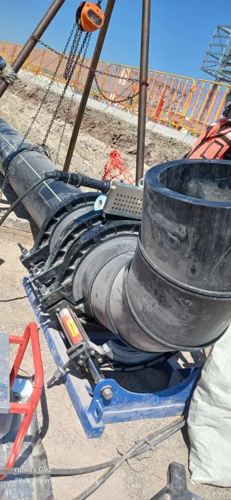 En una obra en construcción se están soldando tubos negros, con estructura metálica y maquinaria.