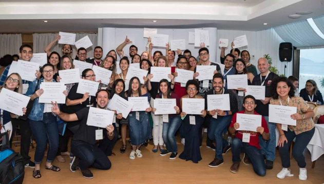 Um grande grupo de pessoas posando para uma foto enquanto seguram certificados.