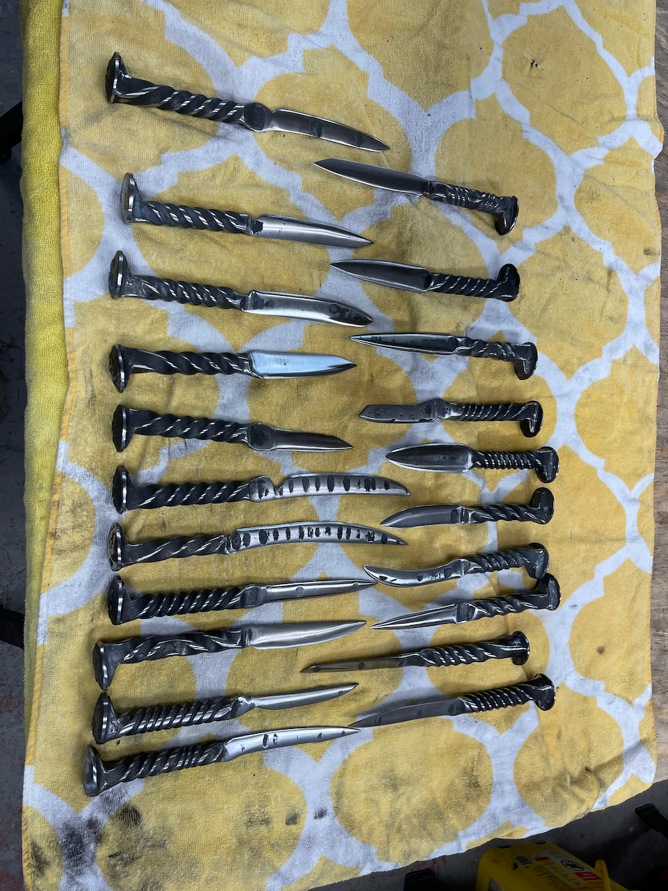 A bunch of nails are lined up on a yellow and white towel.