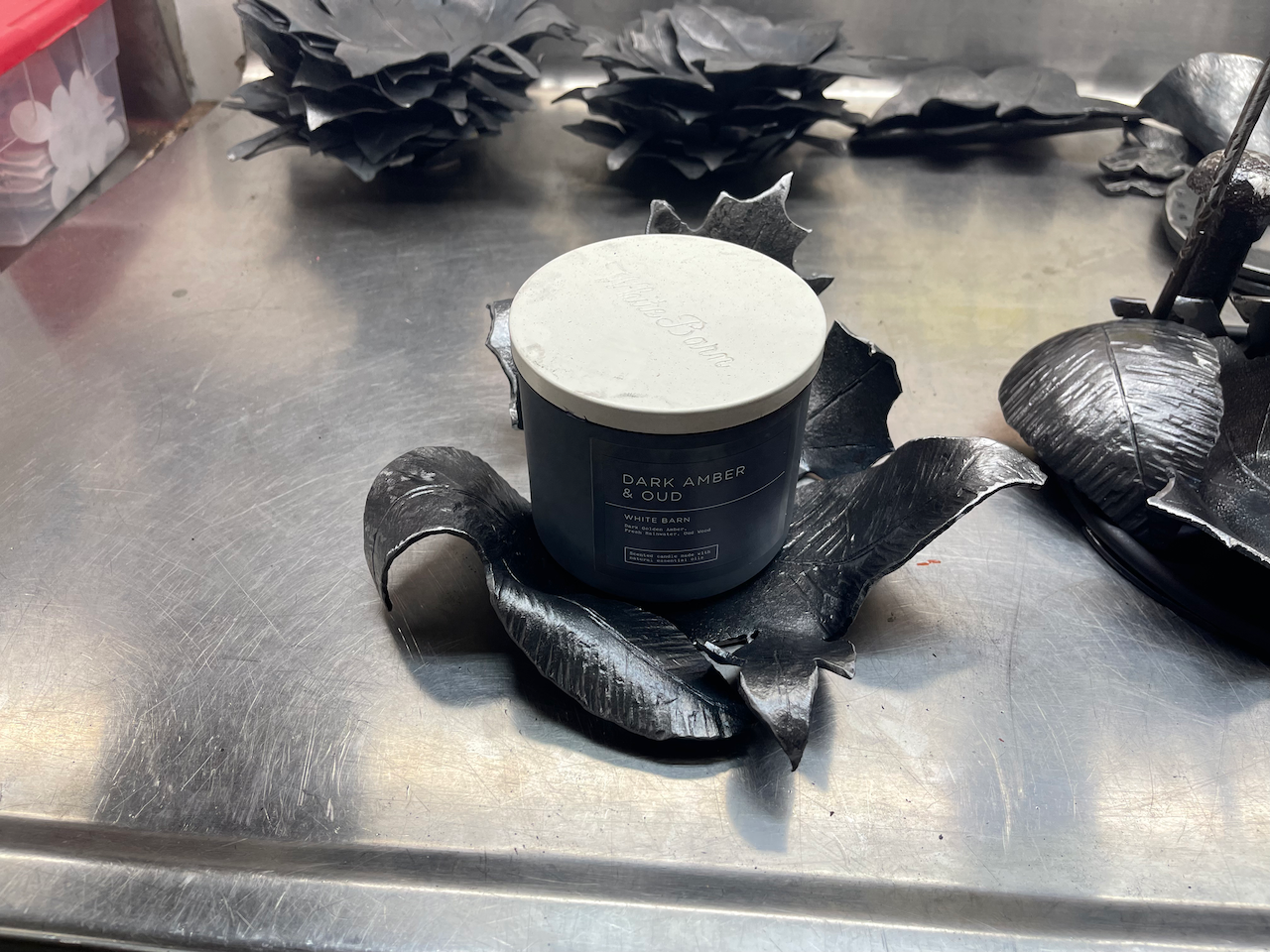 A candle is sitting on a stainless steel counter top