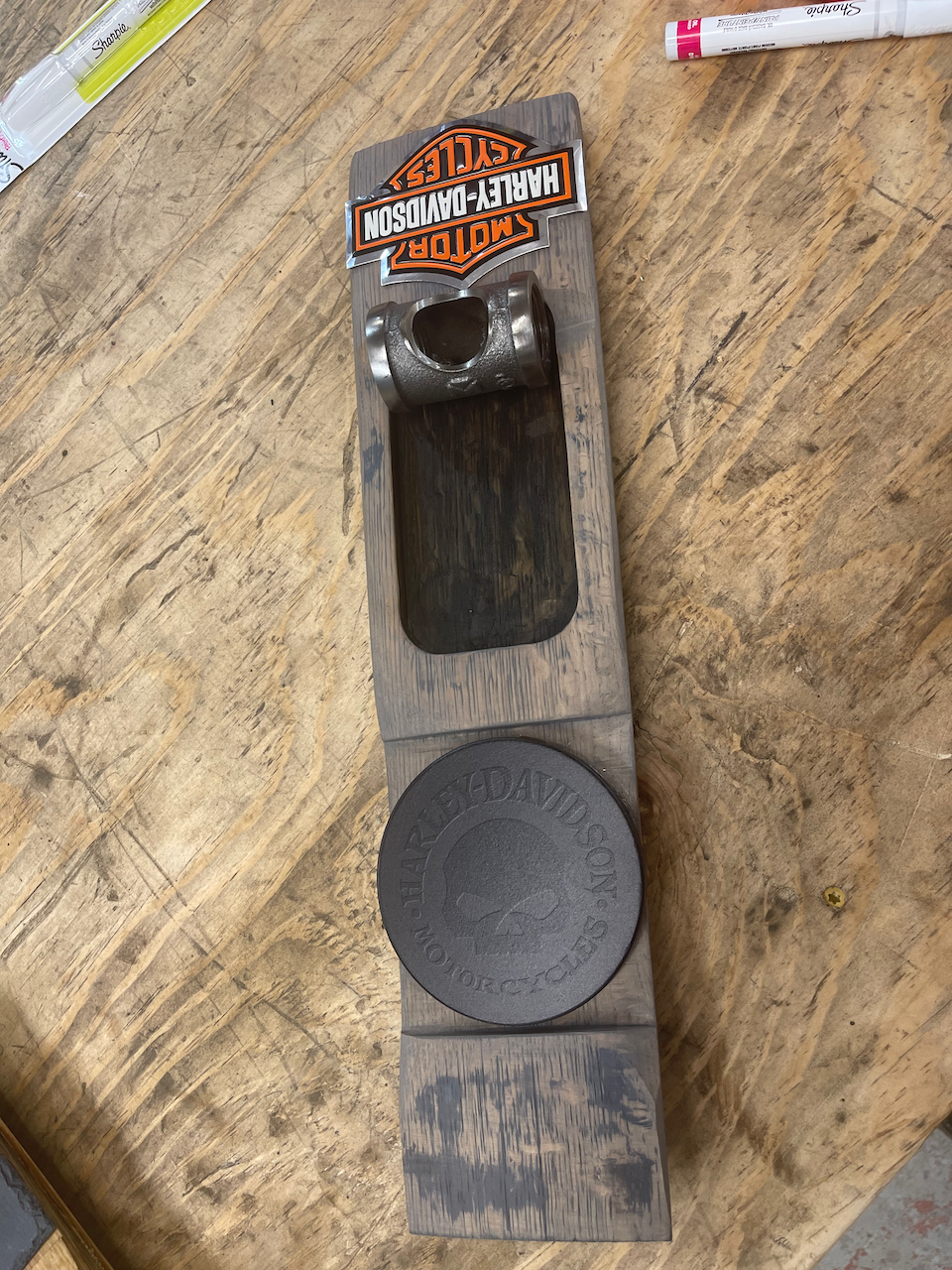 A harley davidson bottle opener is sitting on a wooden table.