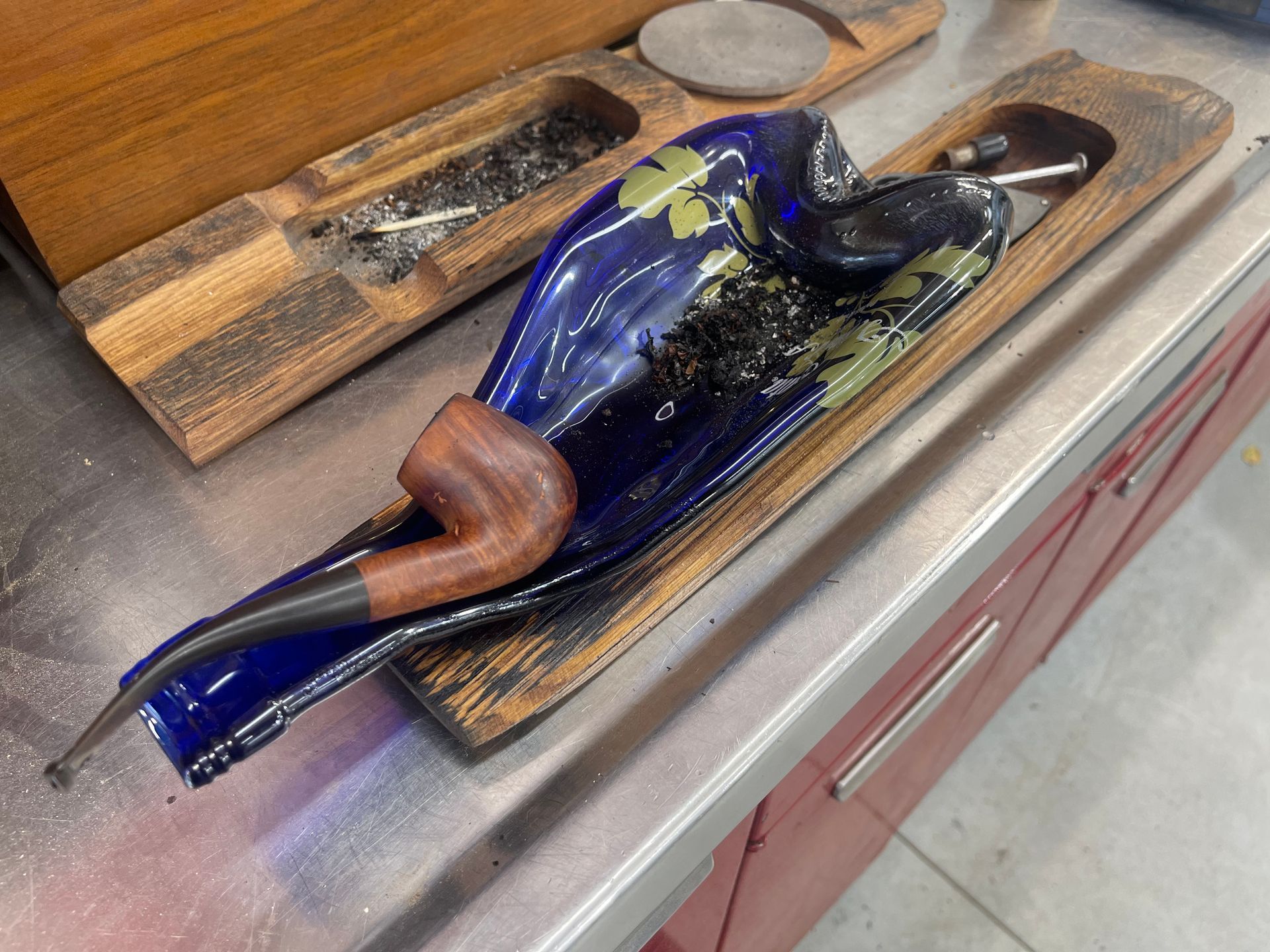 A pipe is sitting on a wooden tray on a counter