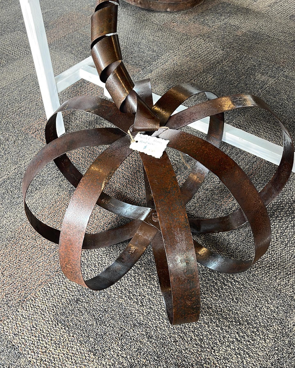 A metal sculpture is sitting on a carpeted floor