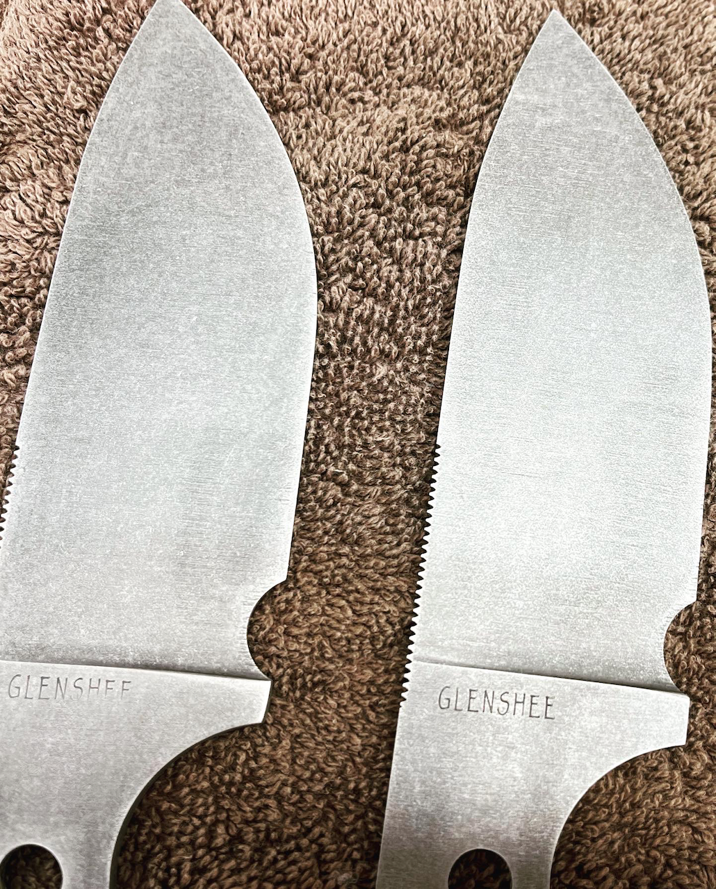 A pair of knives are sitting on a brown carpet.