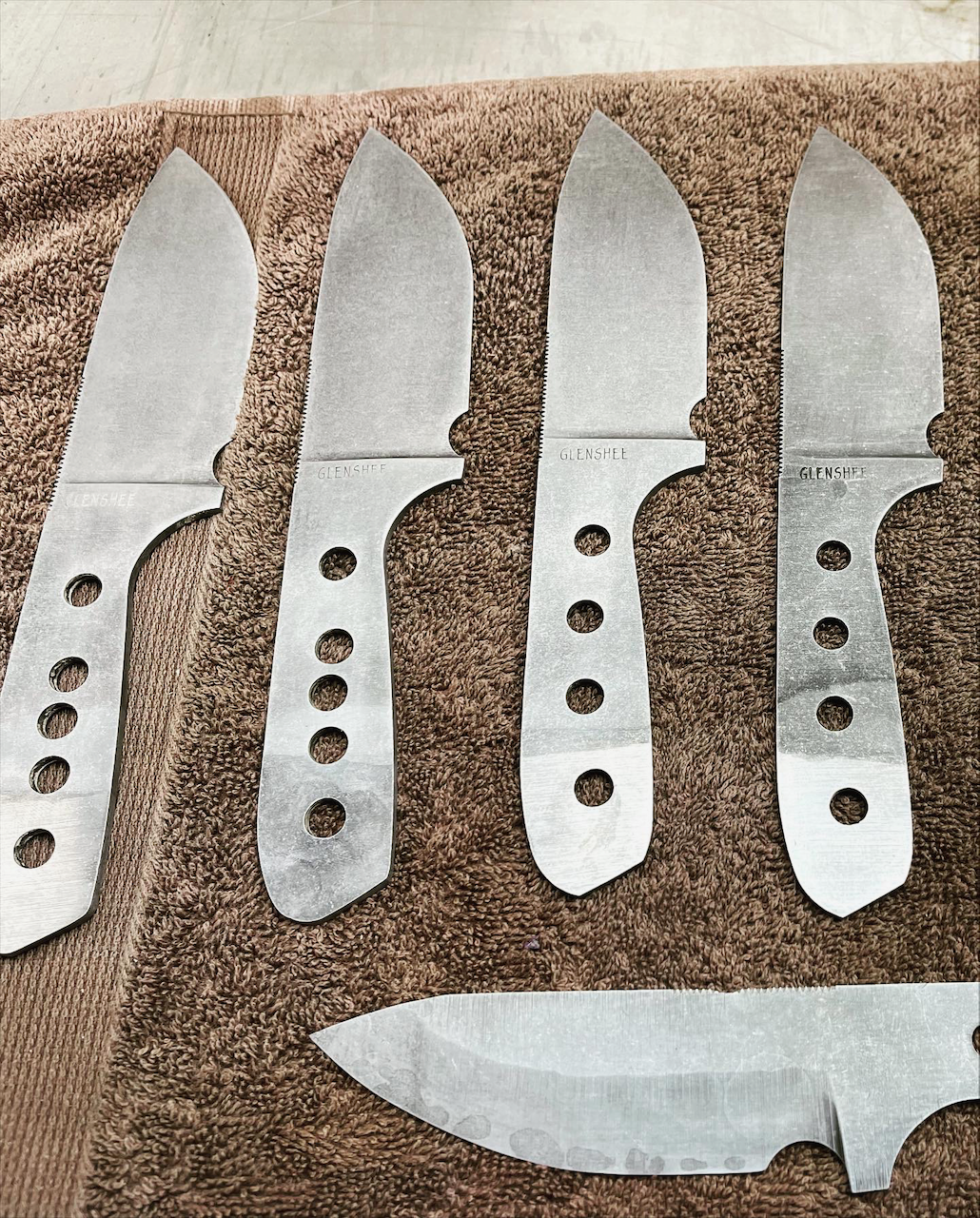 A bunch of knives are lined up on a brown towel