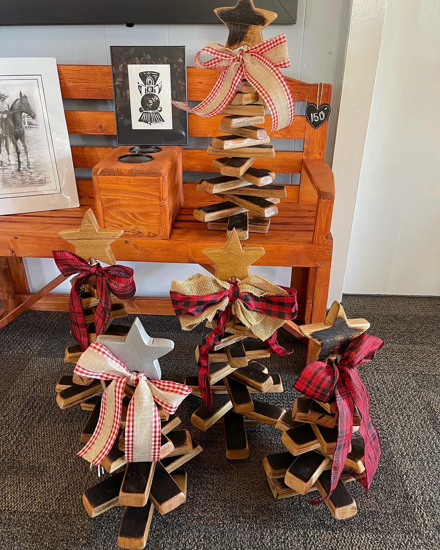 Three wooden christmas trees are sitting on a wooden bench.
