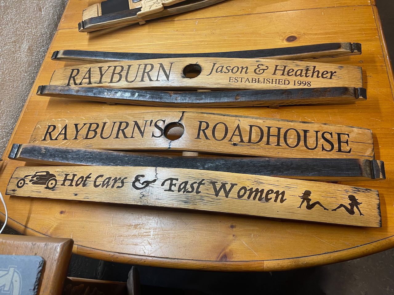 Three wooden signs are sitting on a wooden table.