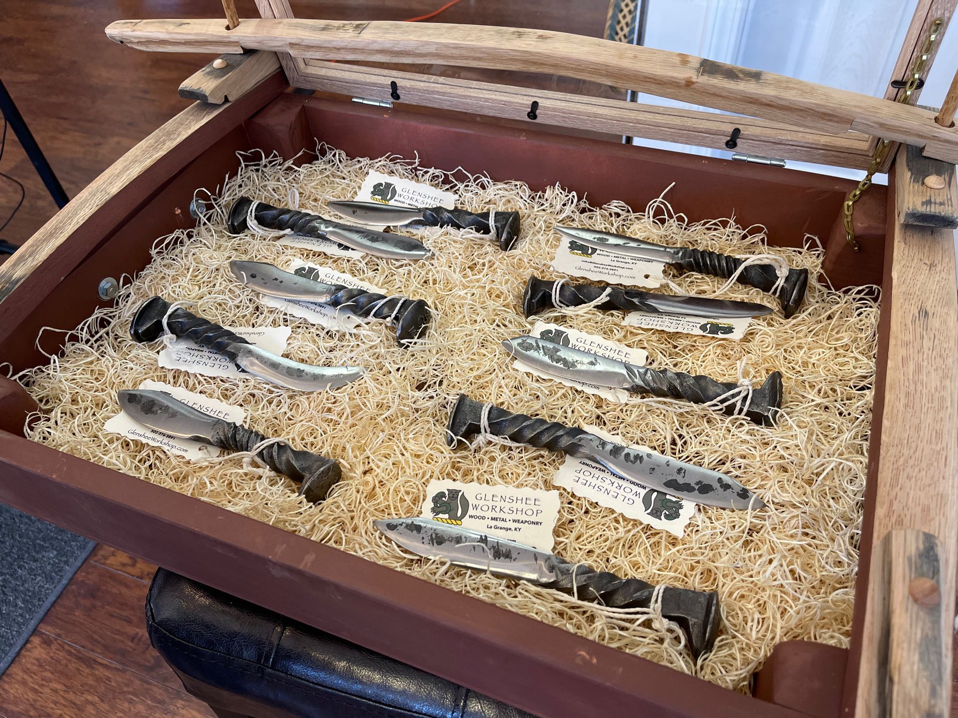 A wooden tray filled with hay and knives.