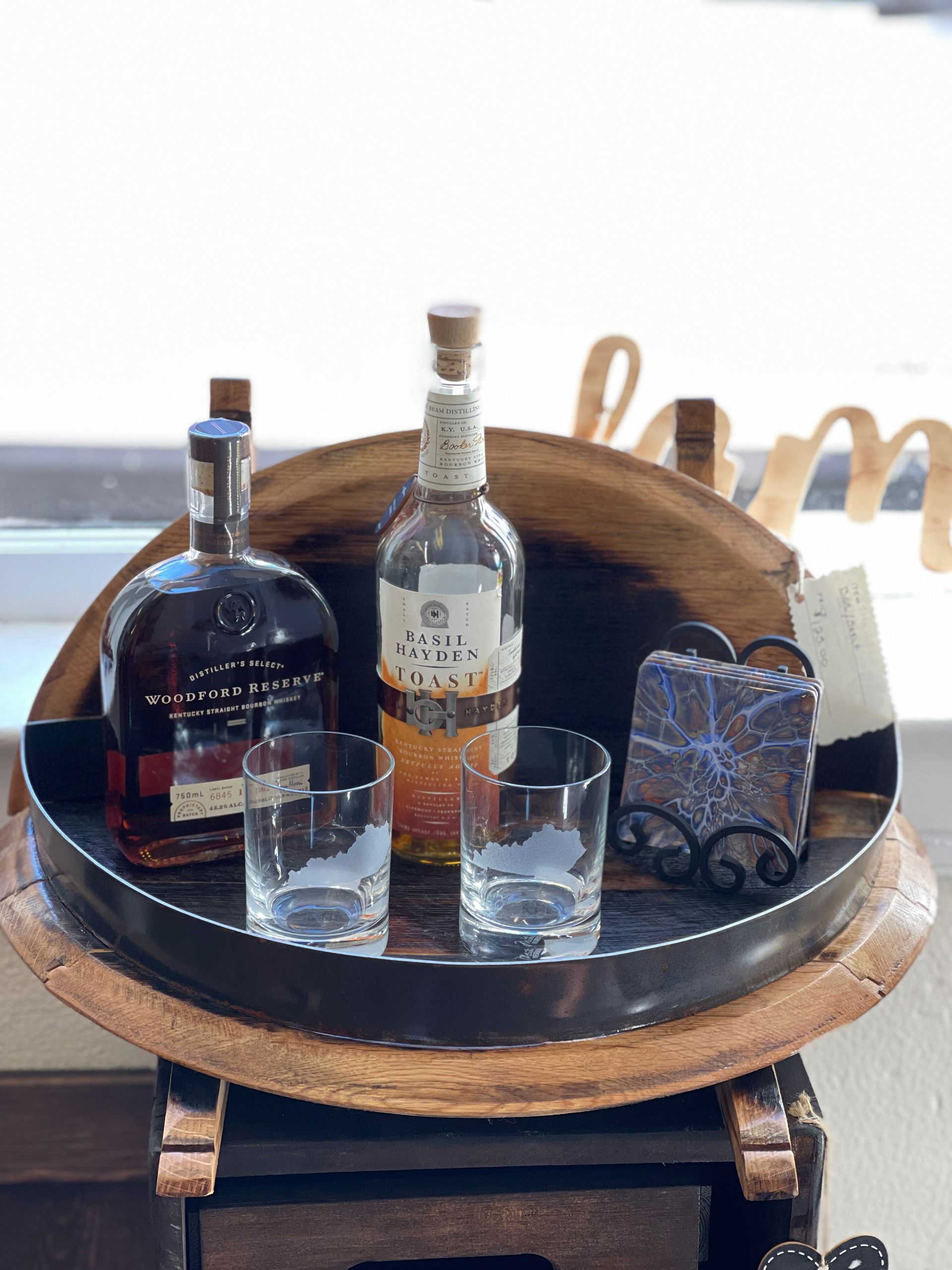 Two bottles of whiskey and two glasses are on a wooden tray.