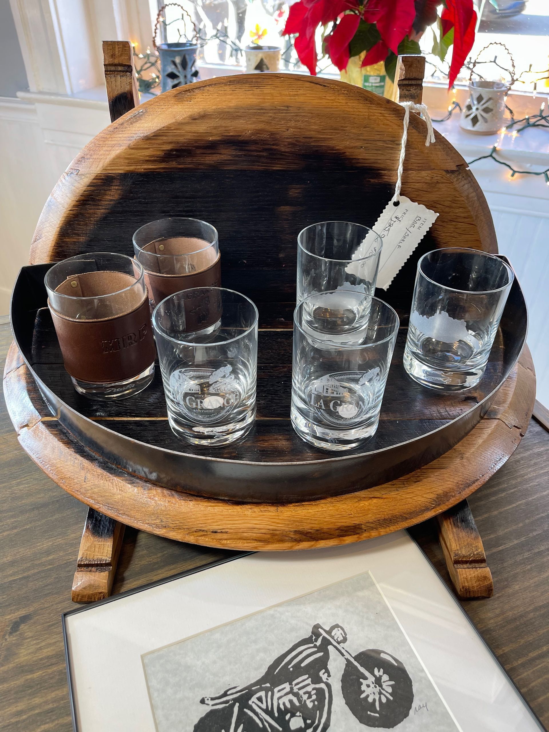 A wooden barrel filled with shot glasses and a picture of a motorcycle.