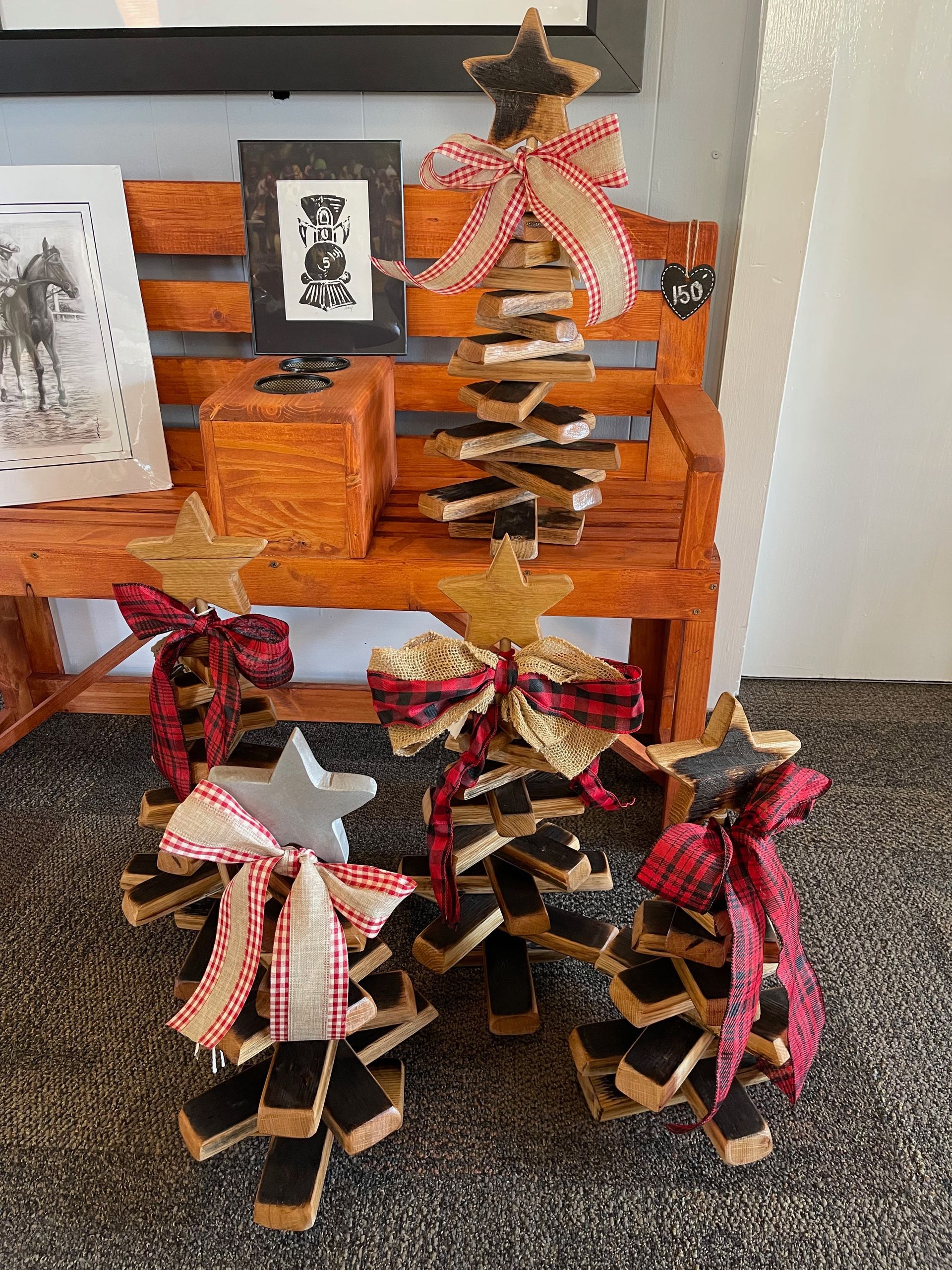 Three wooden christmas trees are sitting on a wooden bench.