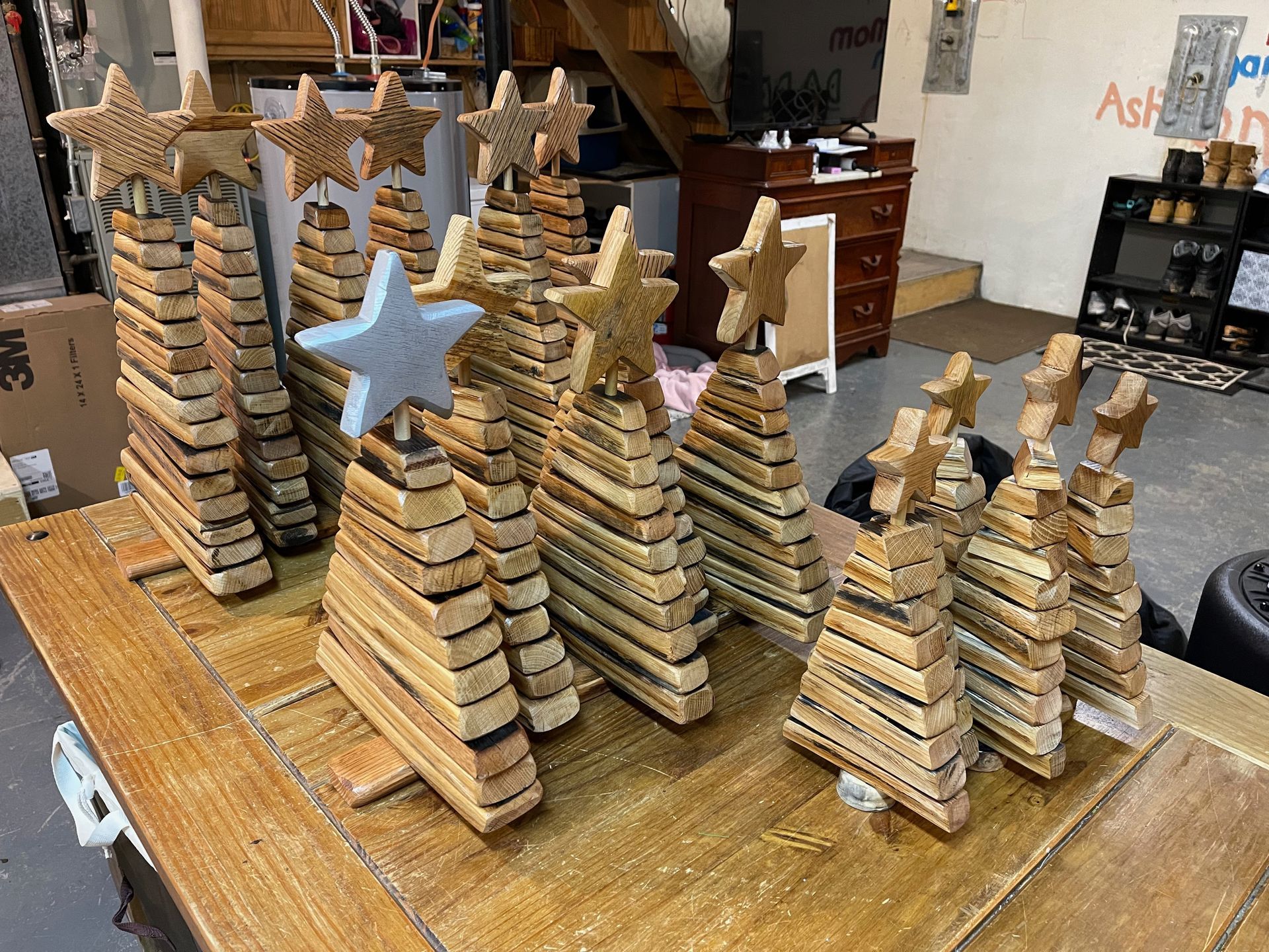 A group of wooden christmas trees with stars on top of them are sitting on a wooden table.