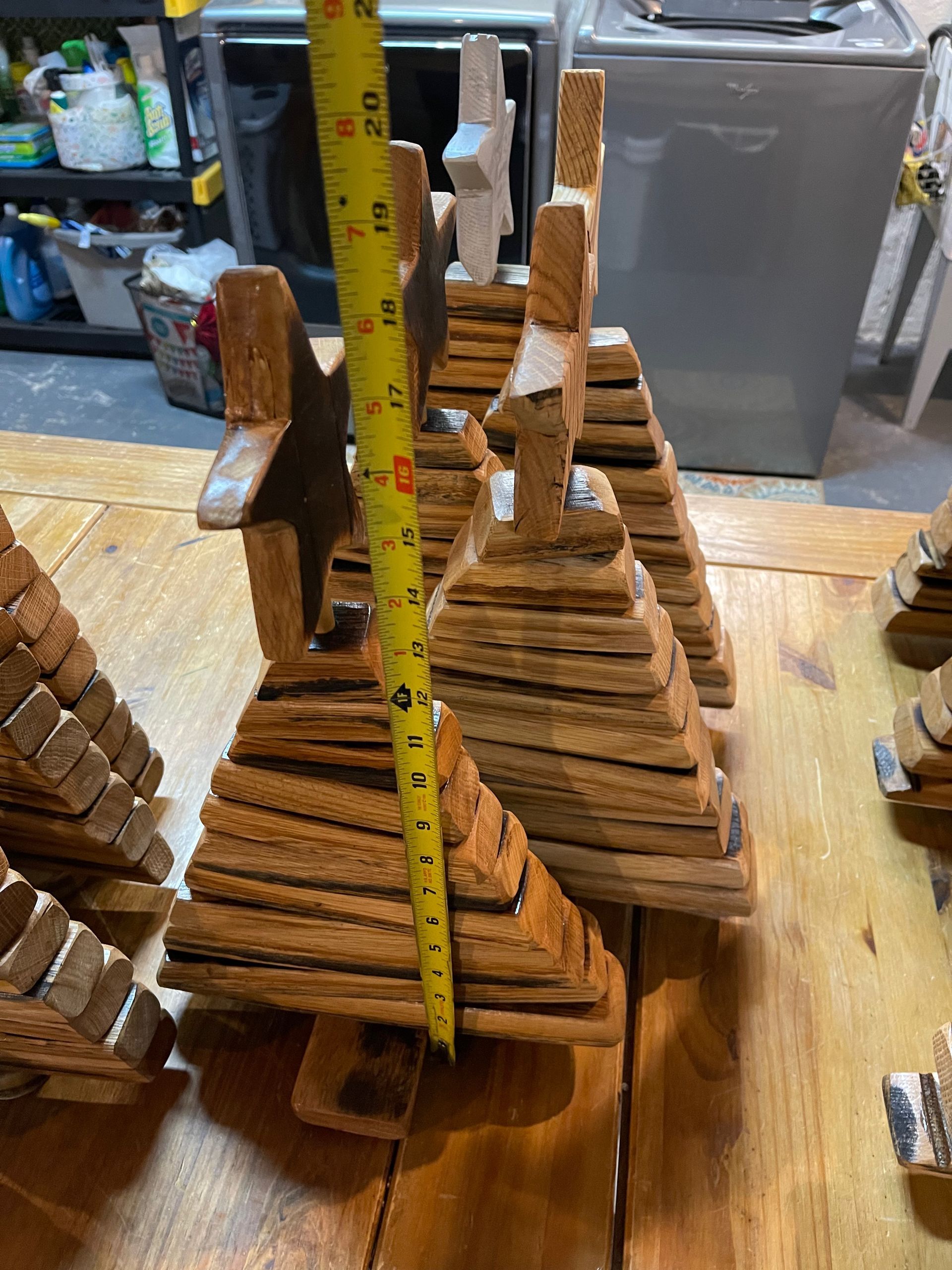 A wooden christmas tree is being measured with a tape measure on a wooden table.