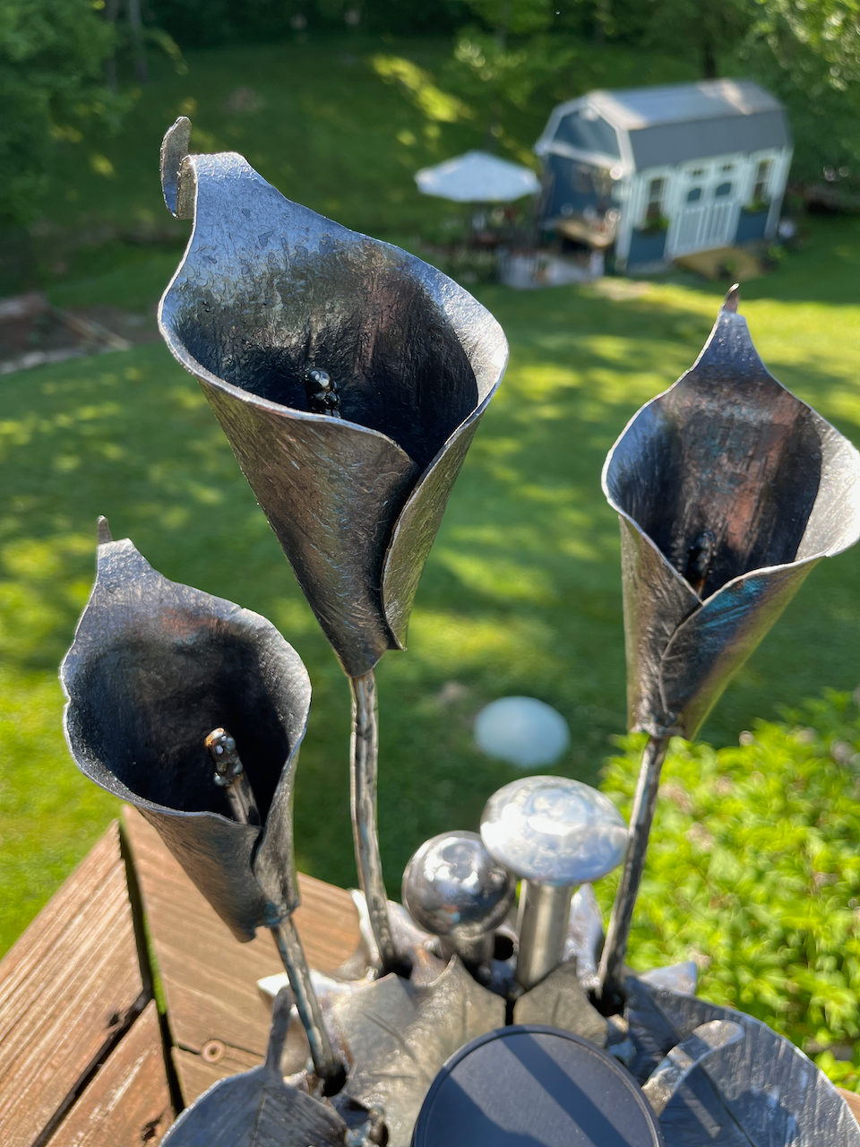 A bunch of metal flowers are sitting on top of a wooden table.