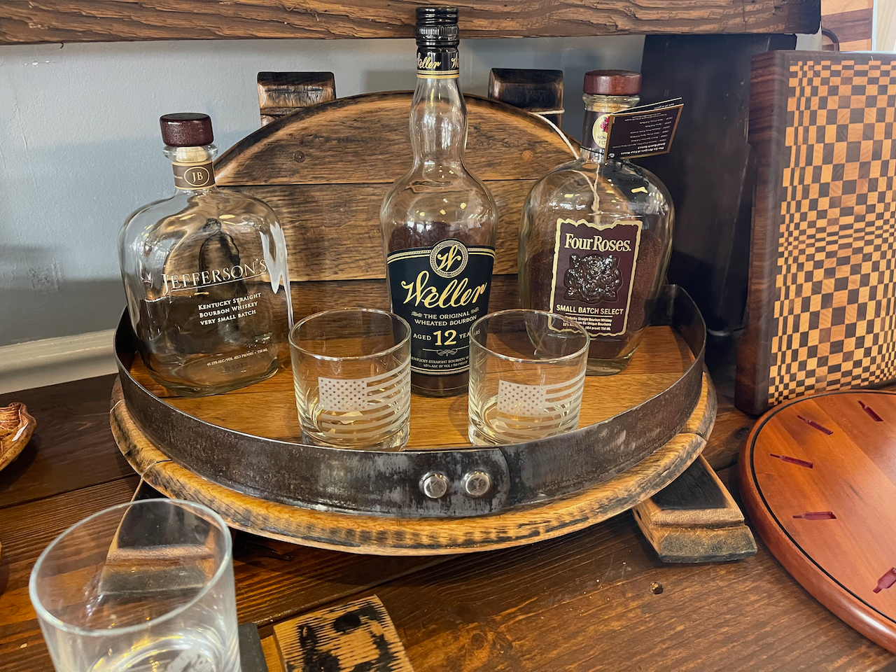 A bottle of whiskey is sitting on top of a wooden barrel.