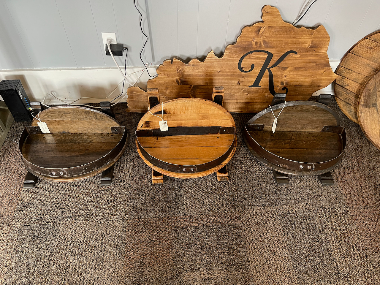 Three wooden barrels are sitting on a carpet next to a wooden sign.